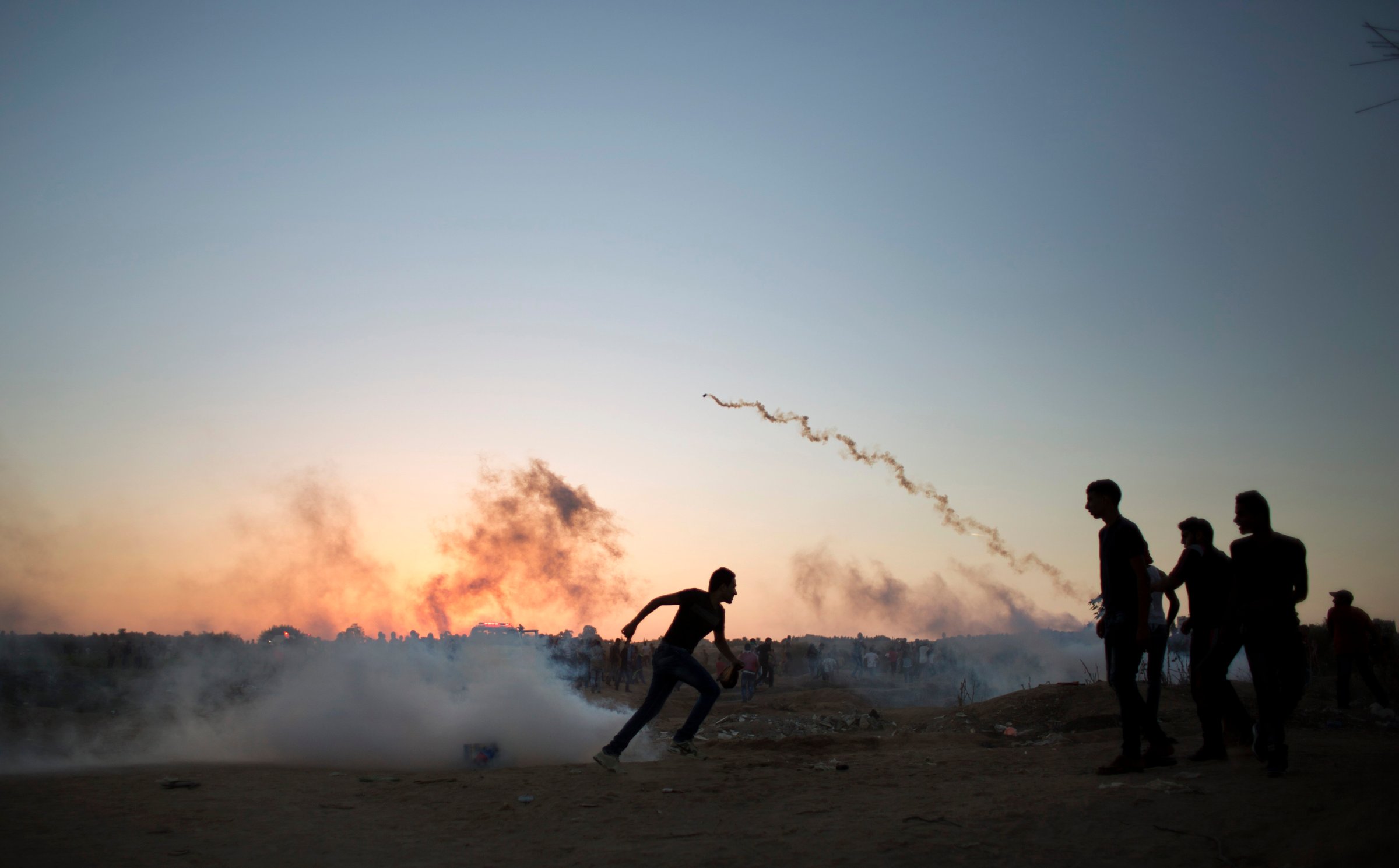 Palestinian protesters run for cover from tear gas fired by Israeli soldiers during clashes on the Israeli border with Gaza in Buriej, central Gaza Strip on Oct. 15, 2015.