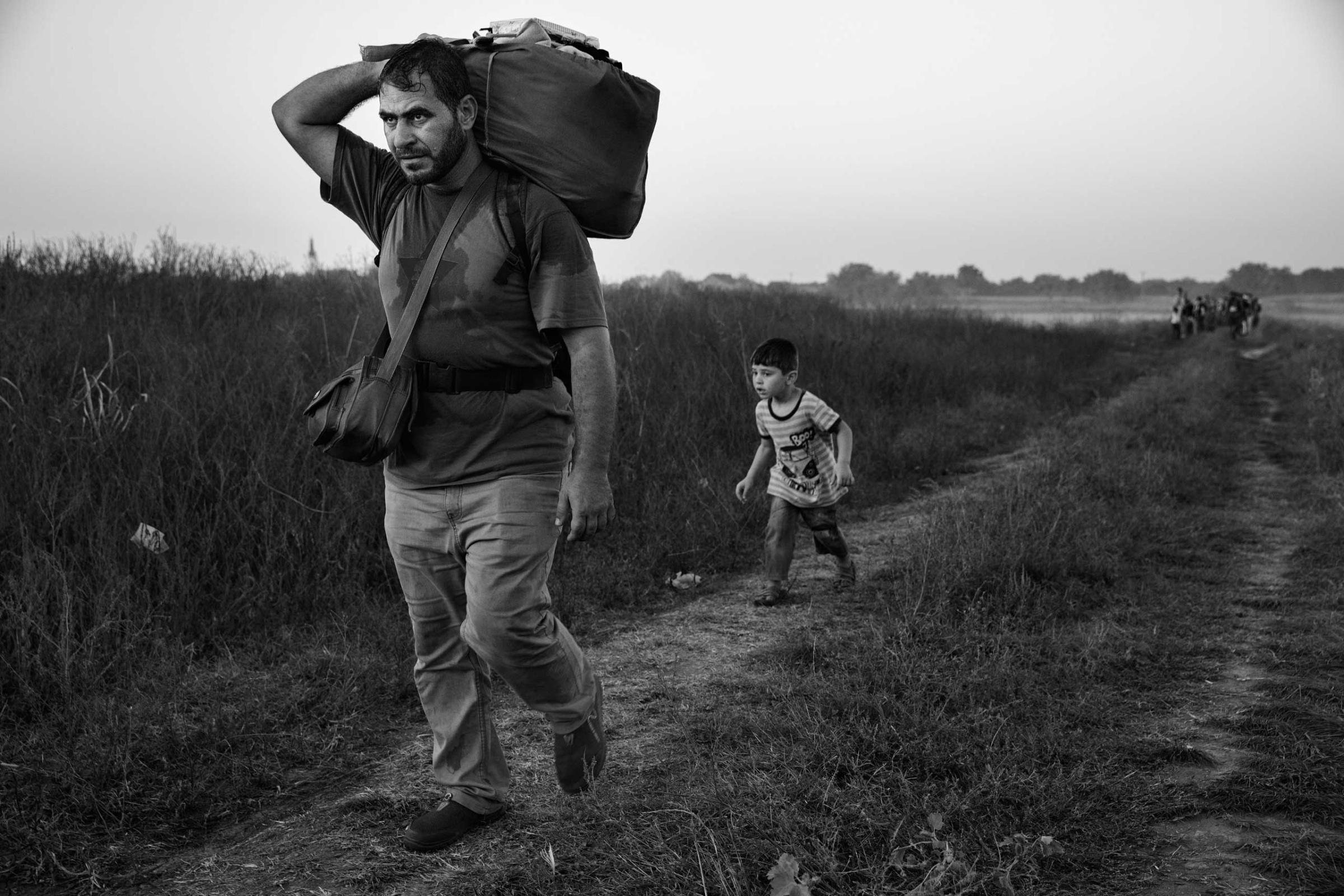 A man walks with his son behind him as they make their way to the train station in Tovarnik, Croatia, on the border with Serbia. In the Balkans, many migrants began traveling by foot, echoing more ancient journeys, September 17, 2015 James Nachtwey for TIME