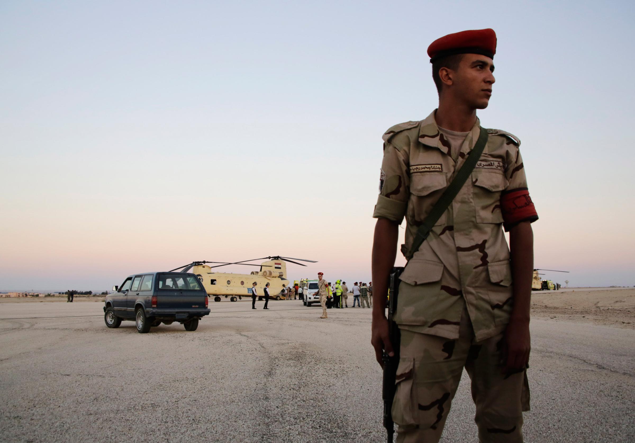 An Egyptian soldier stands guard as emergency workers unload bodies of victims from the crash of a Russian aircraft over the Sinai peninsula from a police helicopter to ambulances at Kabrit military airport, some 20 miles north of Suez, Egypt, Saturday, Oct. 31, 2015. A Russian Metrojet plane crashed Saturday morning in a mountainous region in the Sinai after taking off from Sharm el-Sheikh, killing all 224 people aboard. Officials said the pilot had reported a technical problem and was looking to make an emergency landing before radio contact with air traffic controllers went dead. (AP Photo/Amr Nabil)