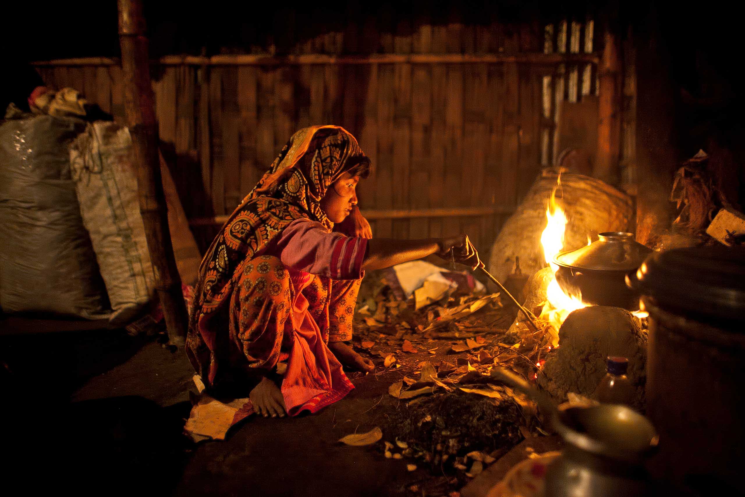 Johanara stokes a cooking fire in her home, Feb. 2015.