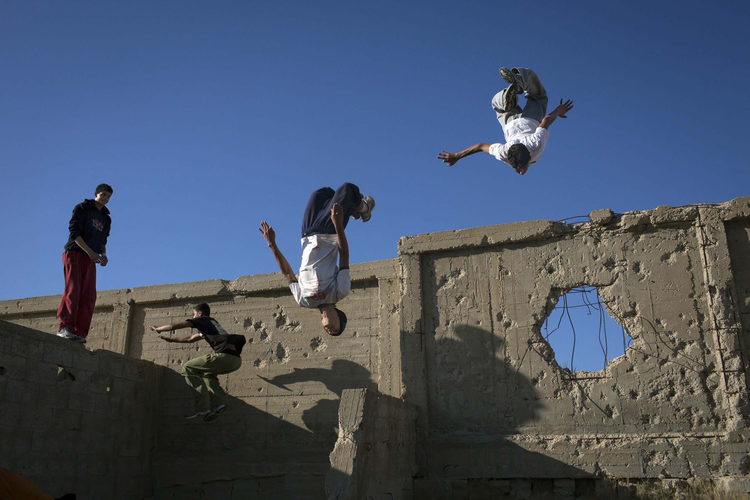 The Gaza Parkour And Free Running team practice in a cemetery on the outskirts of their refugee camp in Khan Younis, Gaza. The walls show damage from past Israeli incursions.
