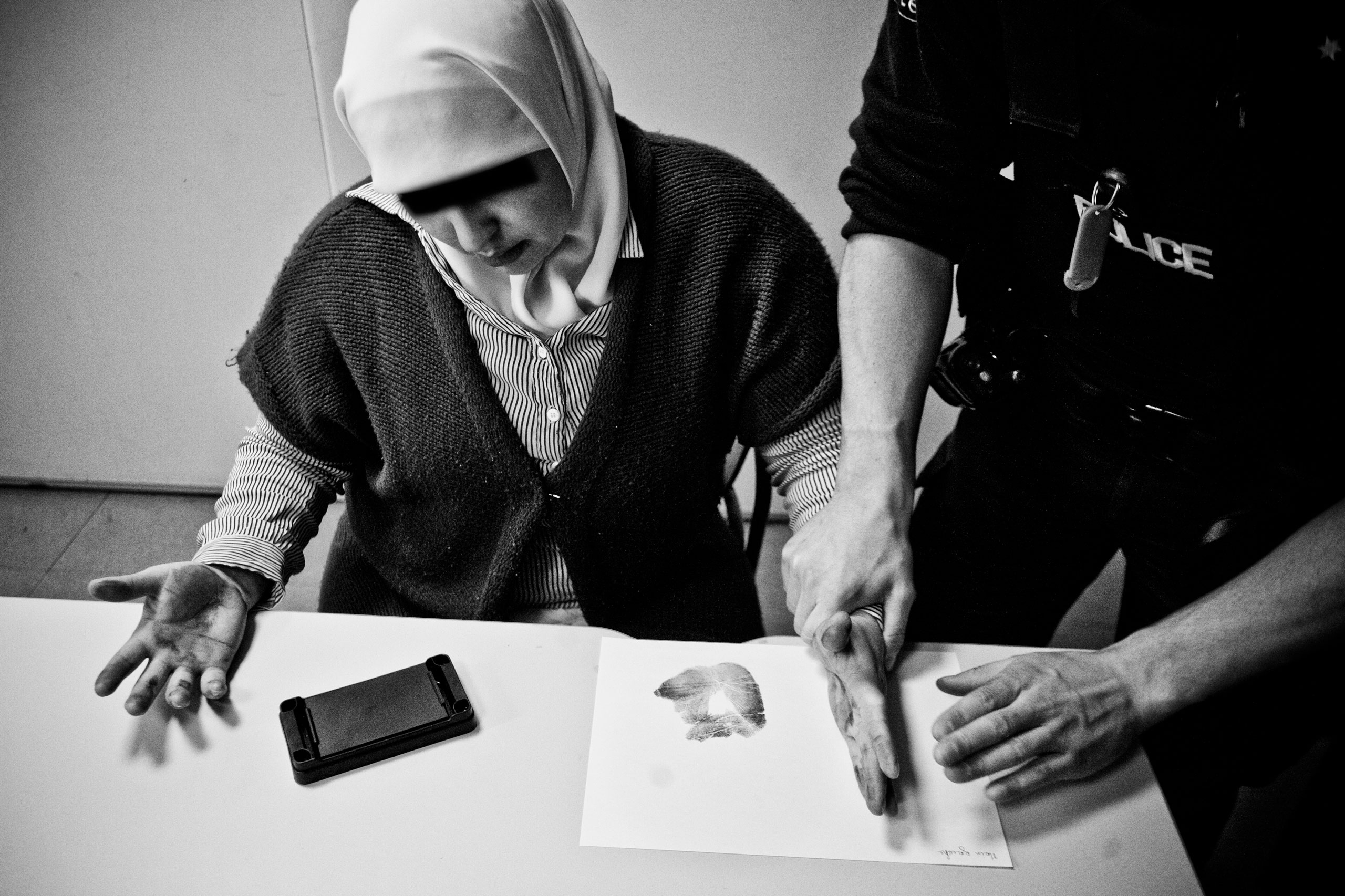 A cop is taking fingerprints of a woman in the police station of Brussels West, Molenbeek, Belgium. Feb 25, 2010. She was involved in a fight at a snack bar.