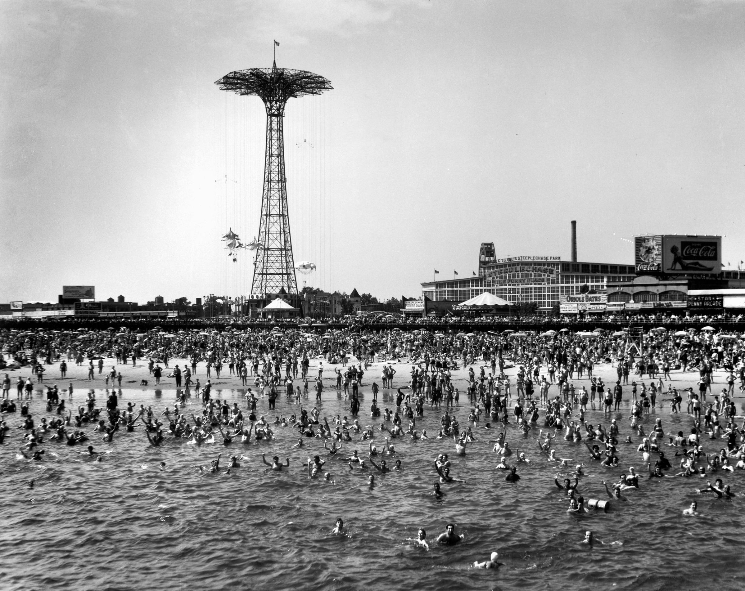 The beach at Coney Island. The parachute ride is visible in the background, 1952.