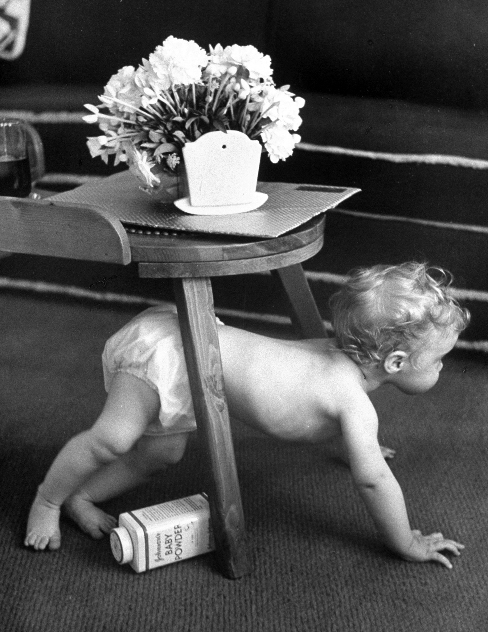 Exploring her house, Linda crawls under table. Flowers adorn gift music box which plays lullaby.