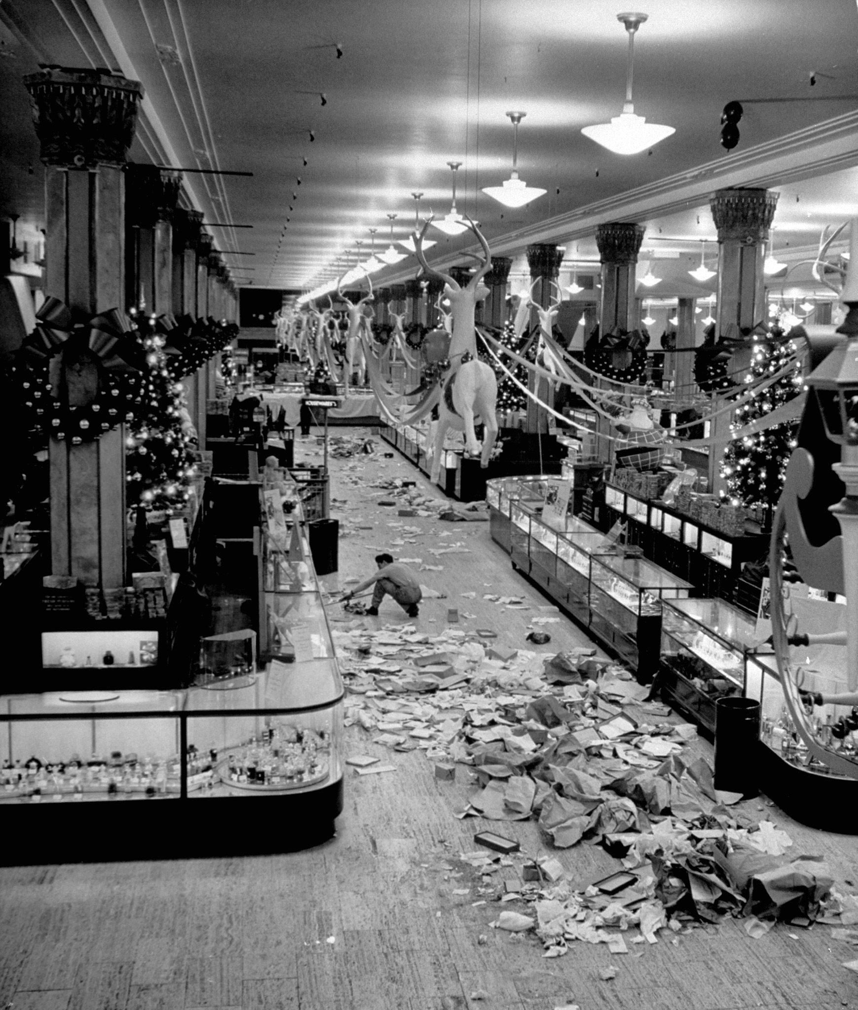 Macy's department store employee cleaning up piles of debris after the Christmas shopping rush, 1948.