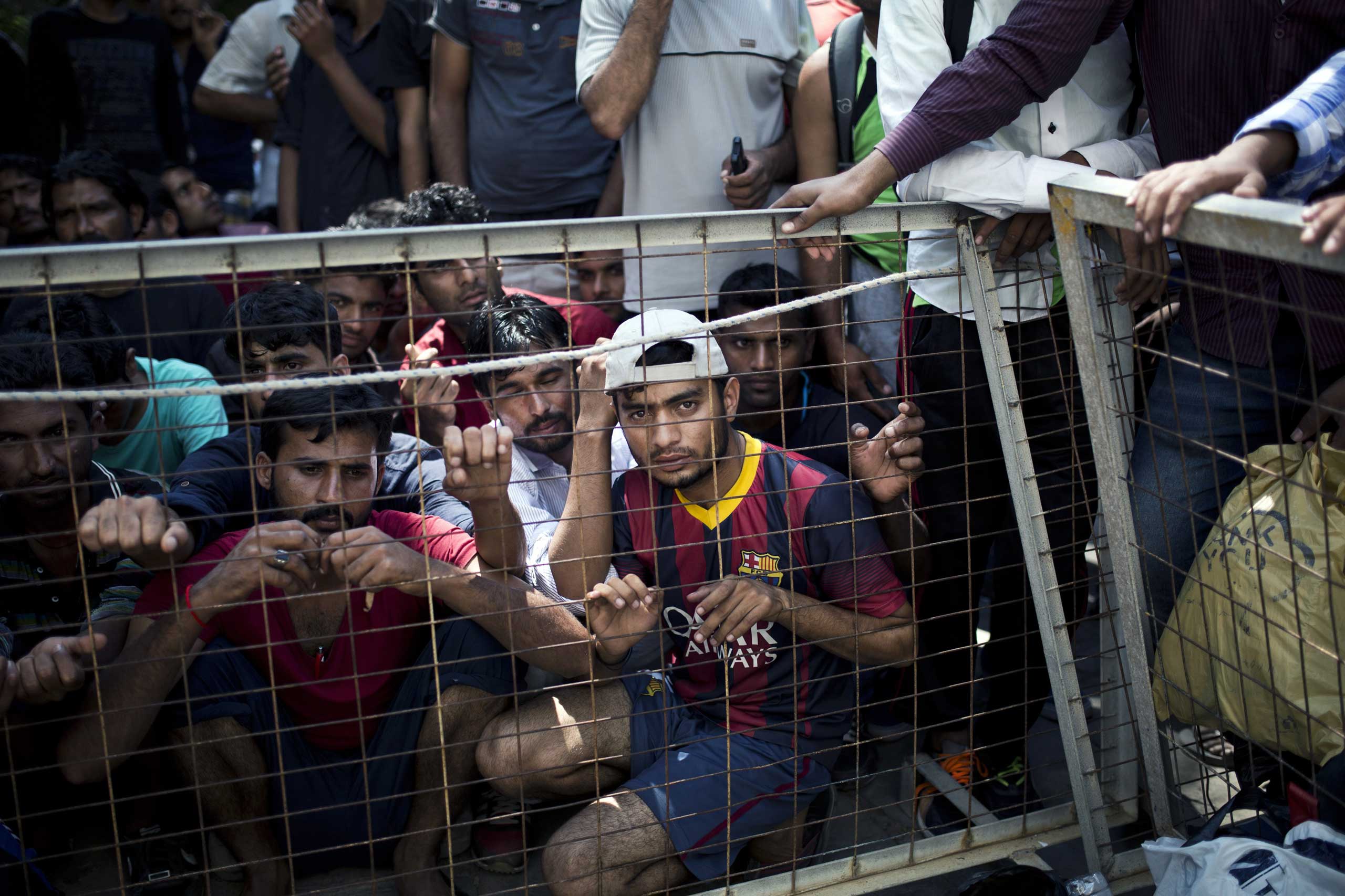 Migrants wait behind a fence to register outside a police station on the island of Kos, Aug. 10 , 2015.