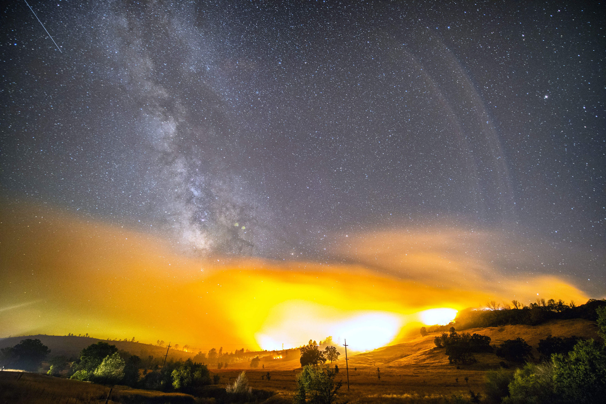 A meteor from the Perseid Meteor shower can be seen in the upper left corner in this long exposure image taken as a wildfire burned in Lake and Napa Counties near the town of Clearlake, Calif. on Aug. 12, 2015.