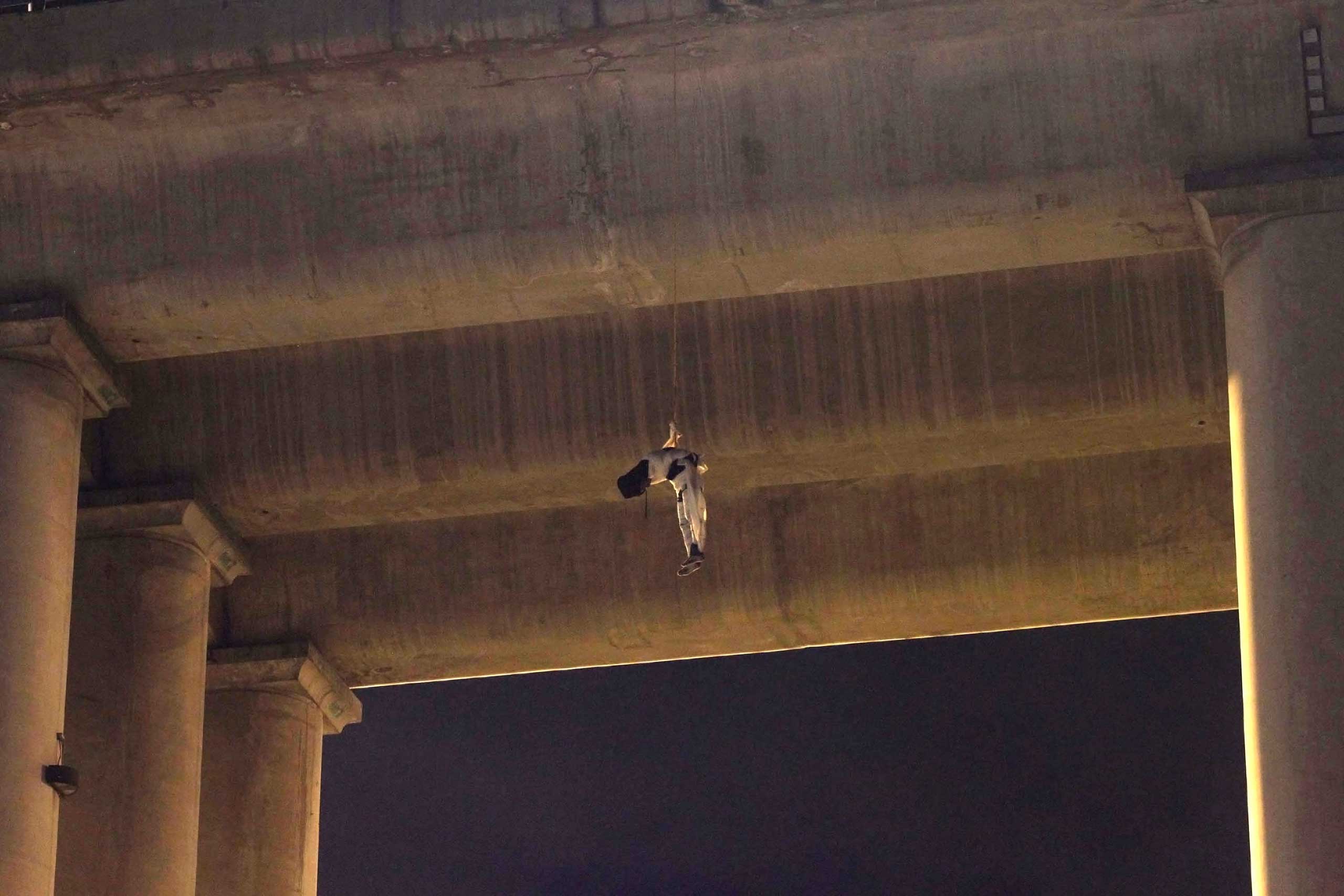 An unidentified dead man hangs from his waist under an overpass in the southern part of Mexico City, on Oct. 19, 2015. (Jair Cabrera—AP)
