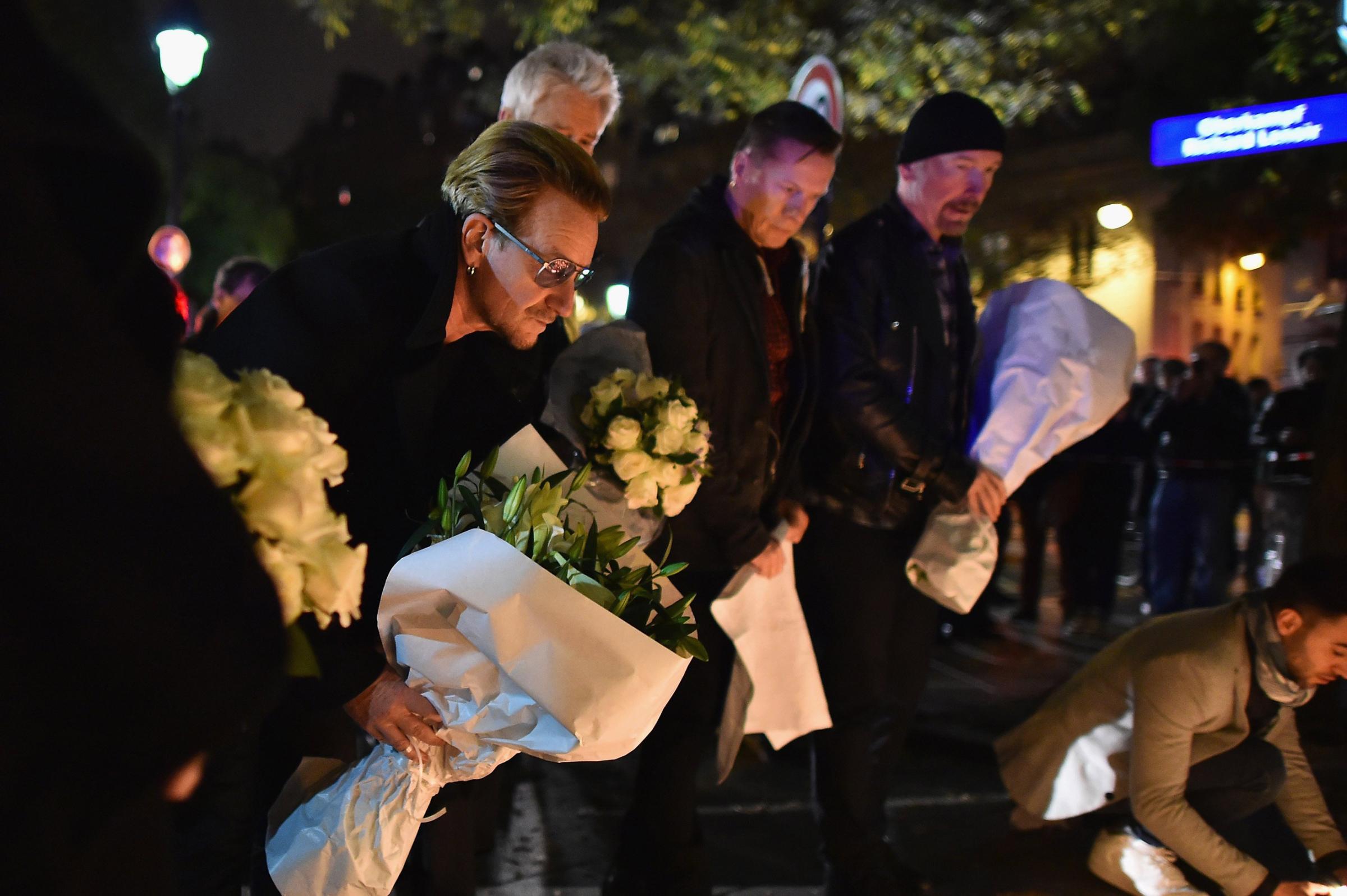 Bono and band members from the band U2 place flowers on the pavement near the scene of yesterday's Bataclan Theatre terrorist attack on Nov. 14, 2015 in Paris.