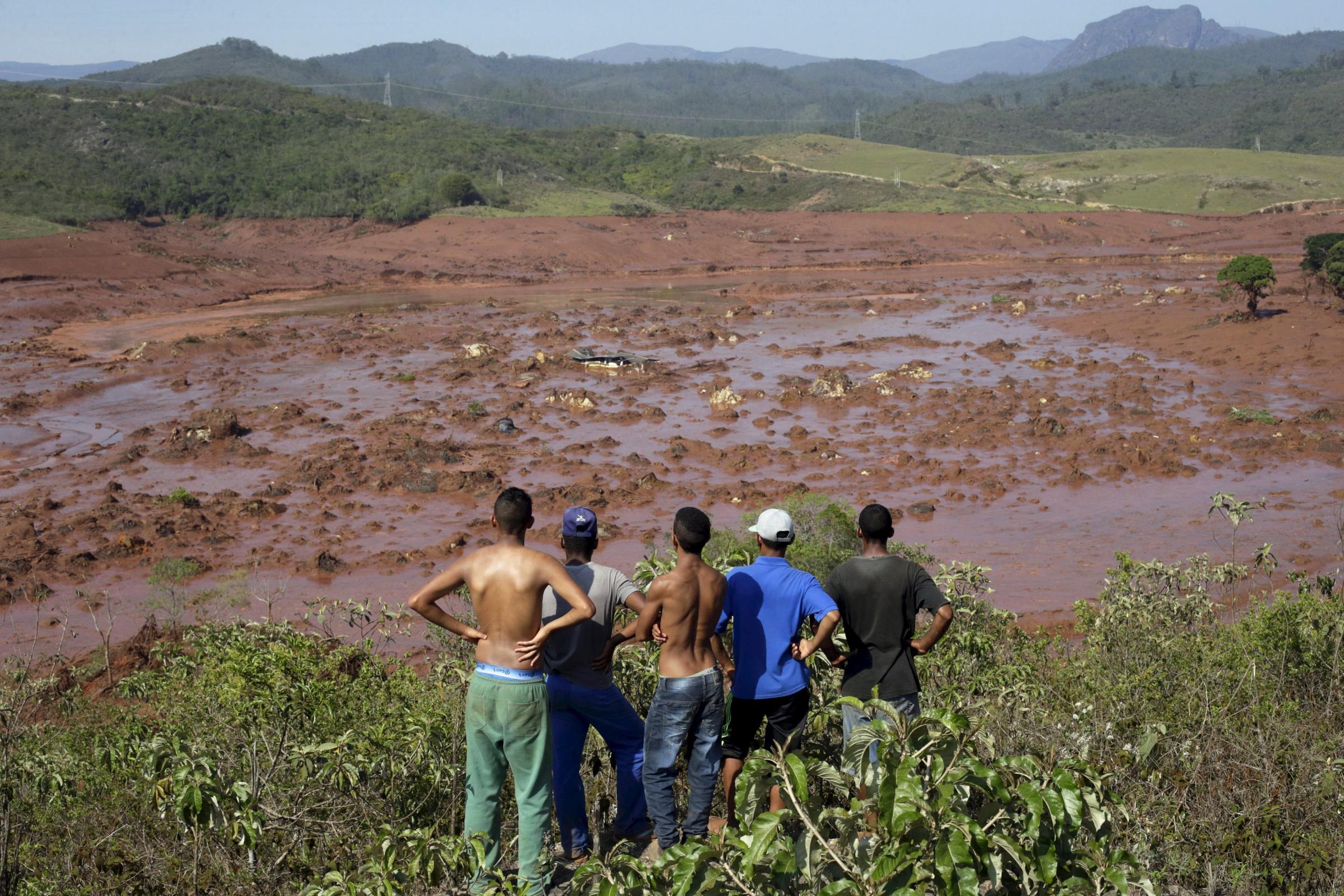 Residents observe the Bento Rodrigues district covered with mud after a dam owned by Vale SA and BHP Billiton Ltd burst in Mariana