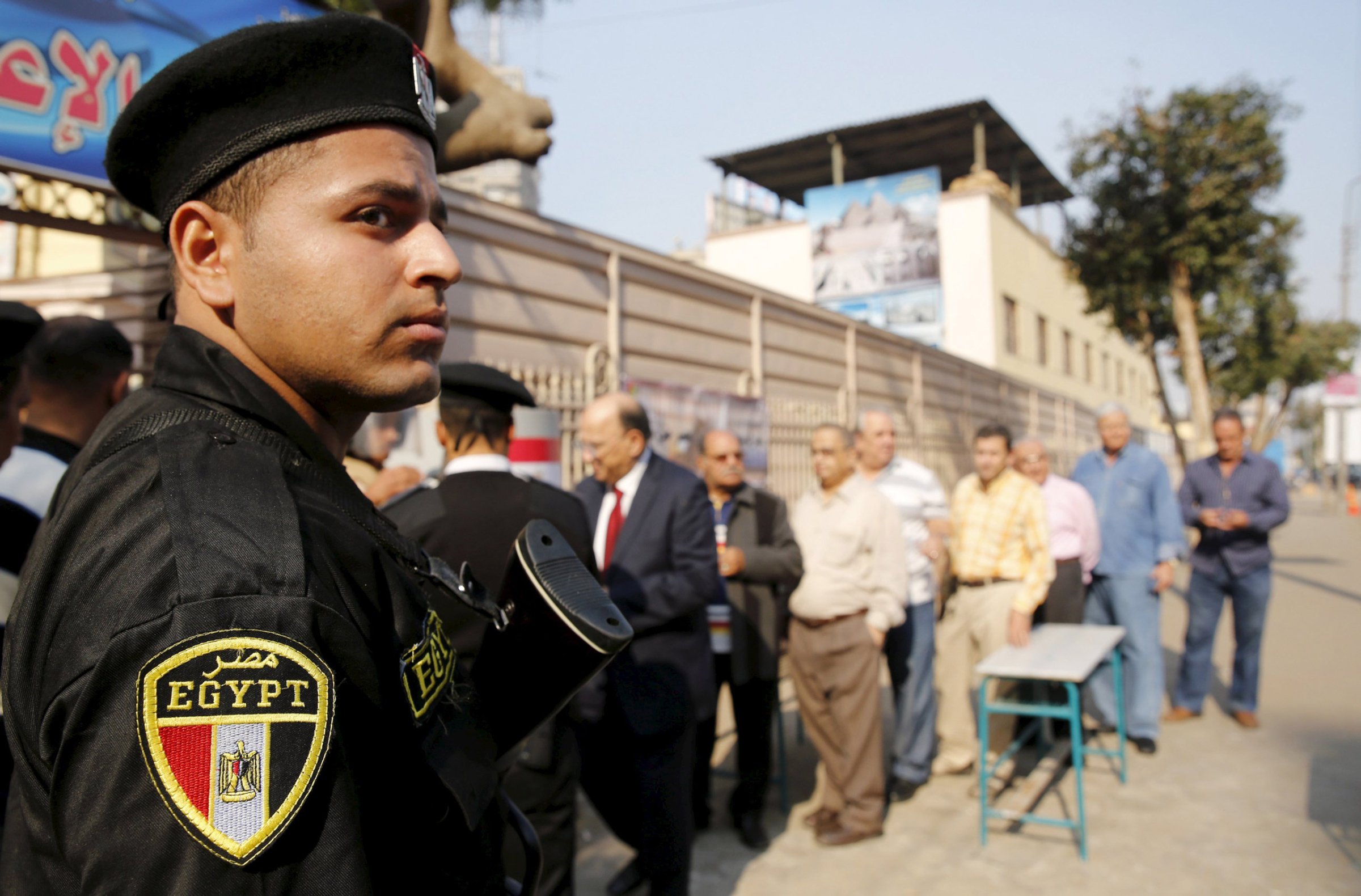 A policeman stands guard in front of people lining up to vote, outside a school being used as a polling station during the second round of parliament elections at Heliopolis in Cairo, Egypt