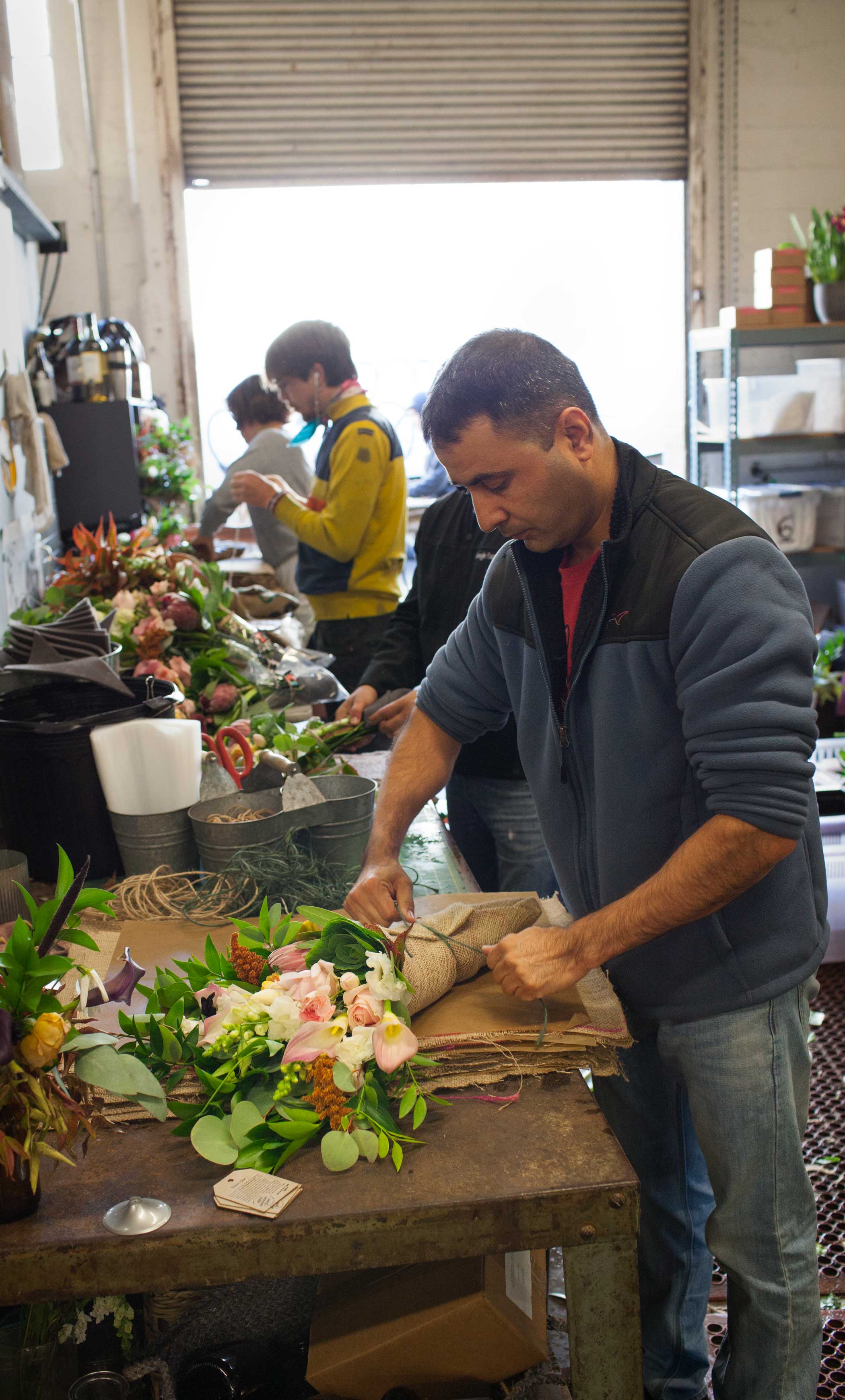 An employee adds wraps a bouquet in burlap before delivery.