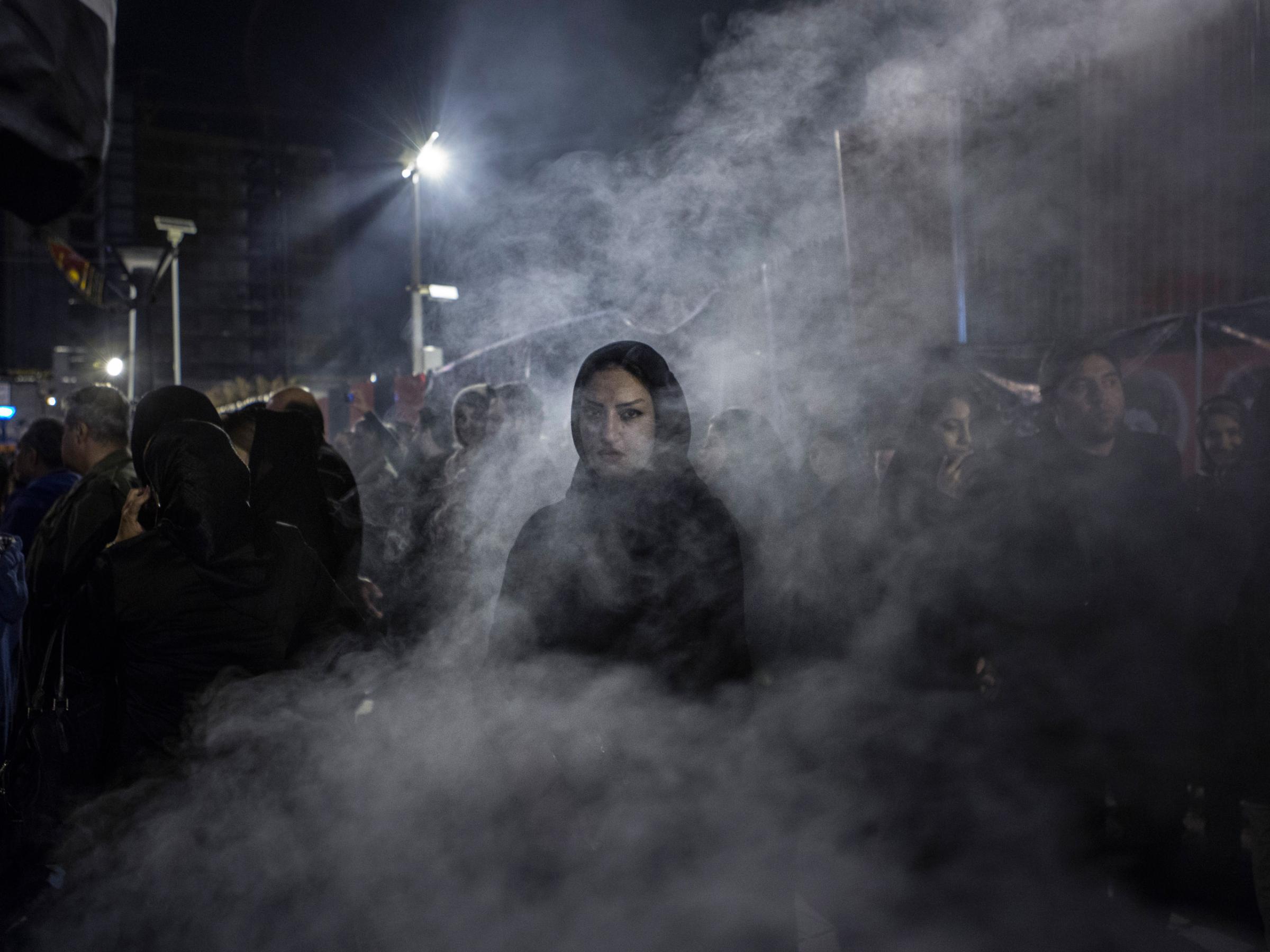 An Iranian women walks through a haze of smoke caused by the burning of 'esfand', a herb. According to popular belief this drives away the evil eye.