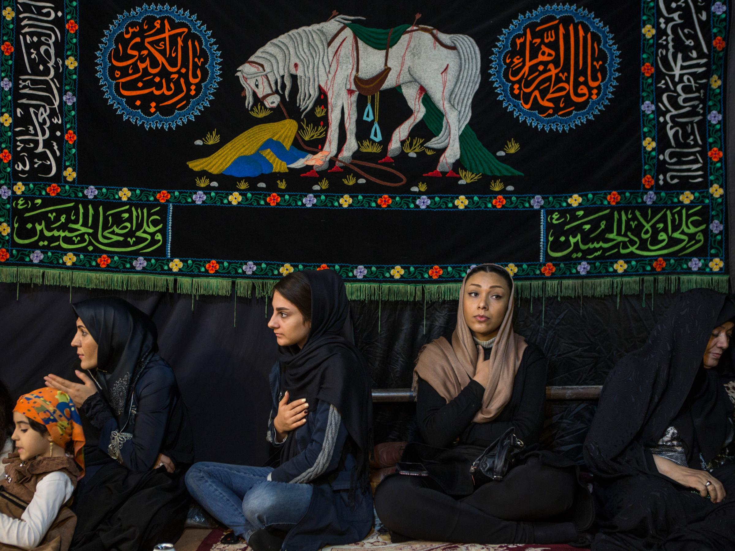 Iranian women beating their chests to commemorate the death of the 3rd and most revered Shiite Imam, Hossein, who people view as a saint here. During ten days of mourning his violent death on the plains of Kerbala in current day Iraq is remembered. Here the women have gathered at a makeshift tent in western Tehran, listening to a female religious chanter.