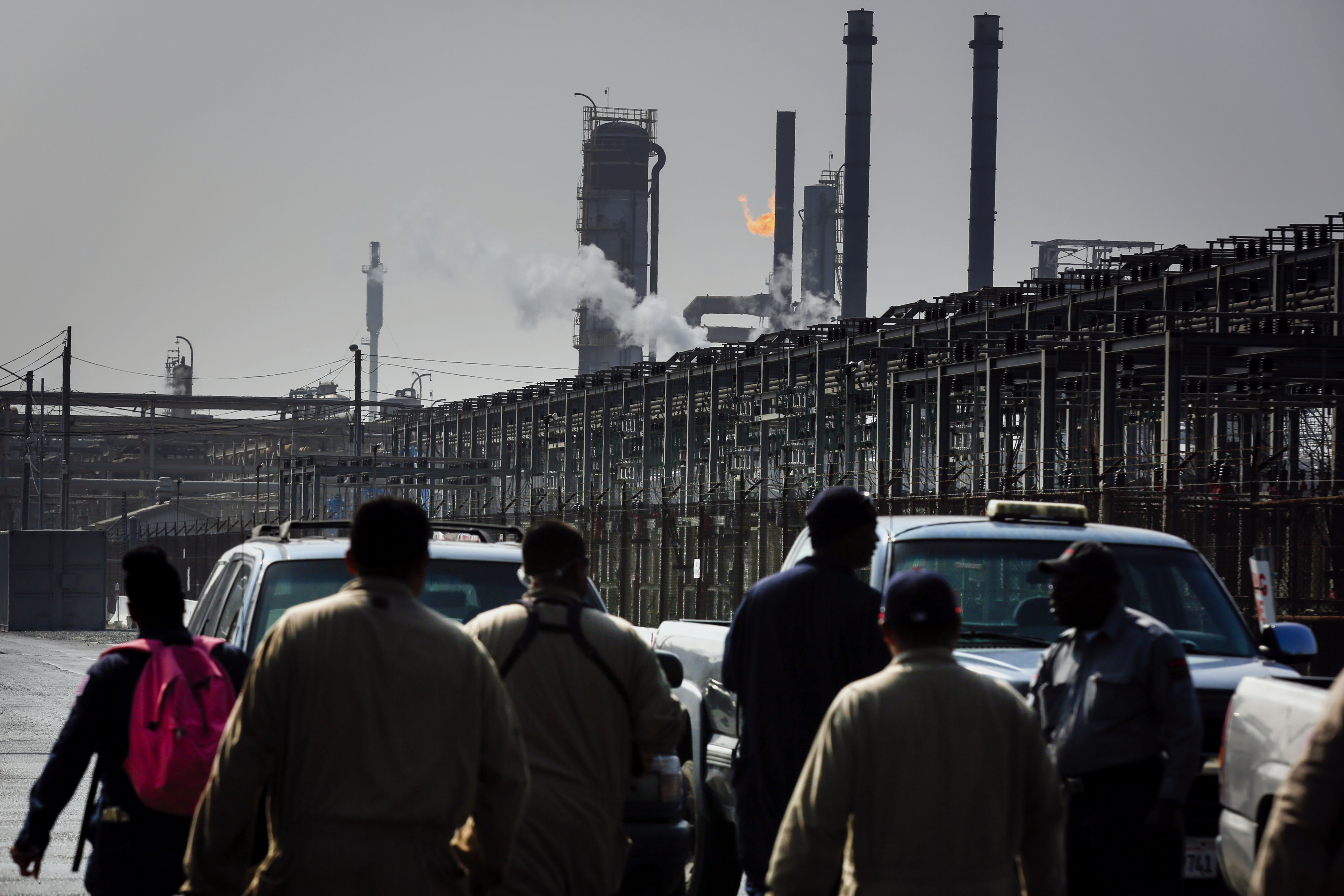 A flare burns overhead as workers enter Gate 7 at the Exxon Mobil Corp. Torrance refinery in Los Angeles on Feb. 18, 2015. (Patrick T. Fallon—Bloomberg/Getty Images)