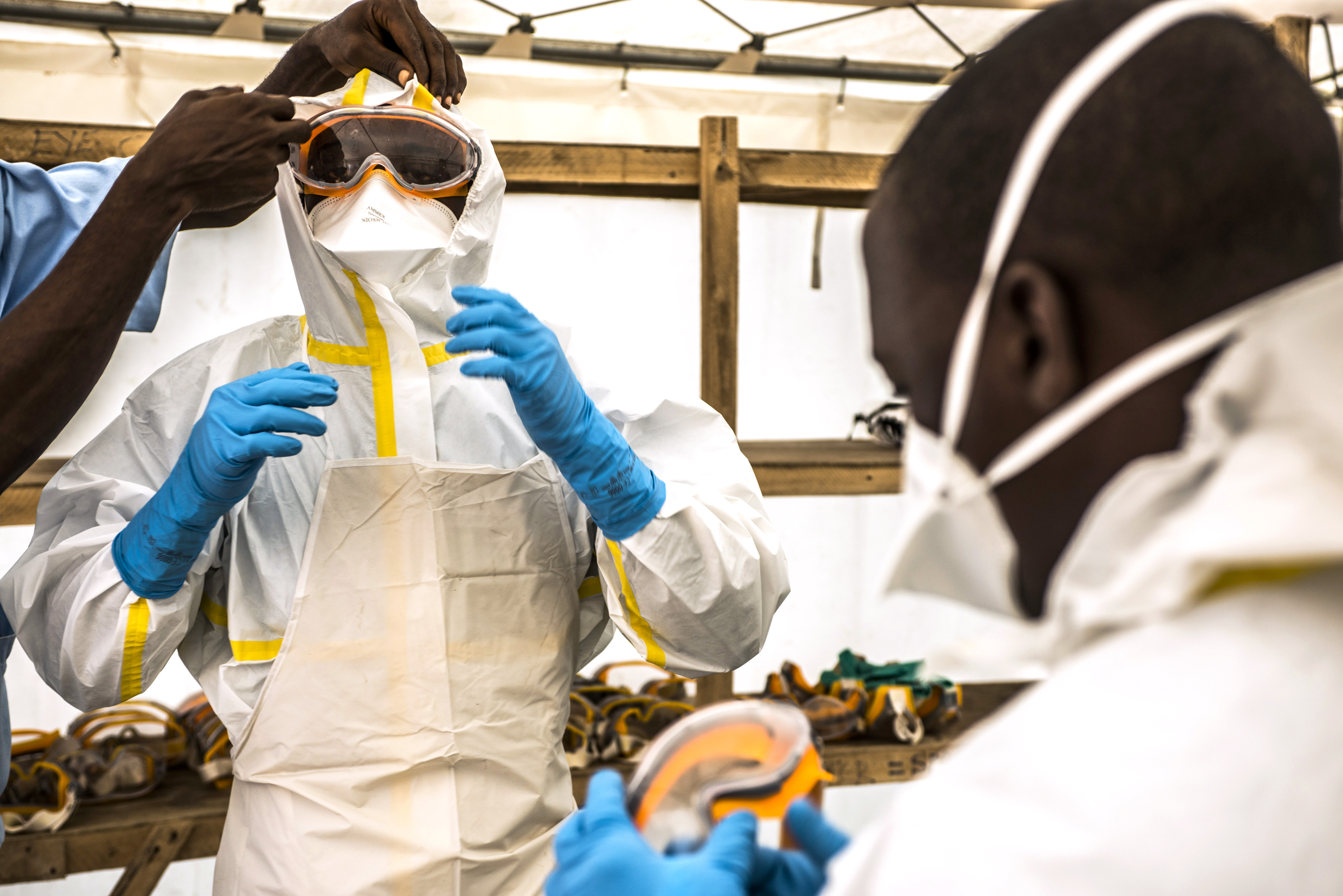 A healthcare worker helps a colleague dress in protective gear at an Ebola treatment center in Guinea, Sept. 10, 2015 (Bloomberg—Getty Images)