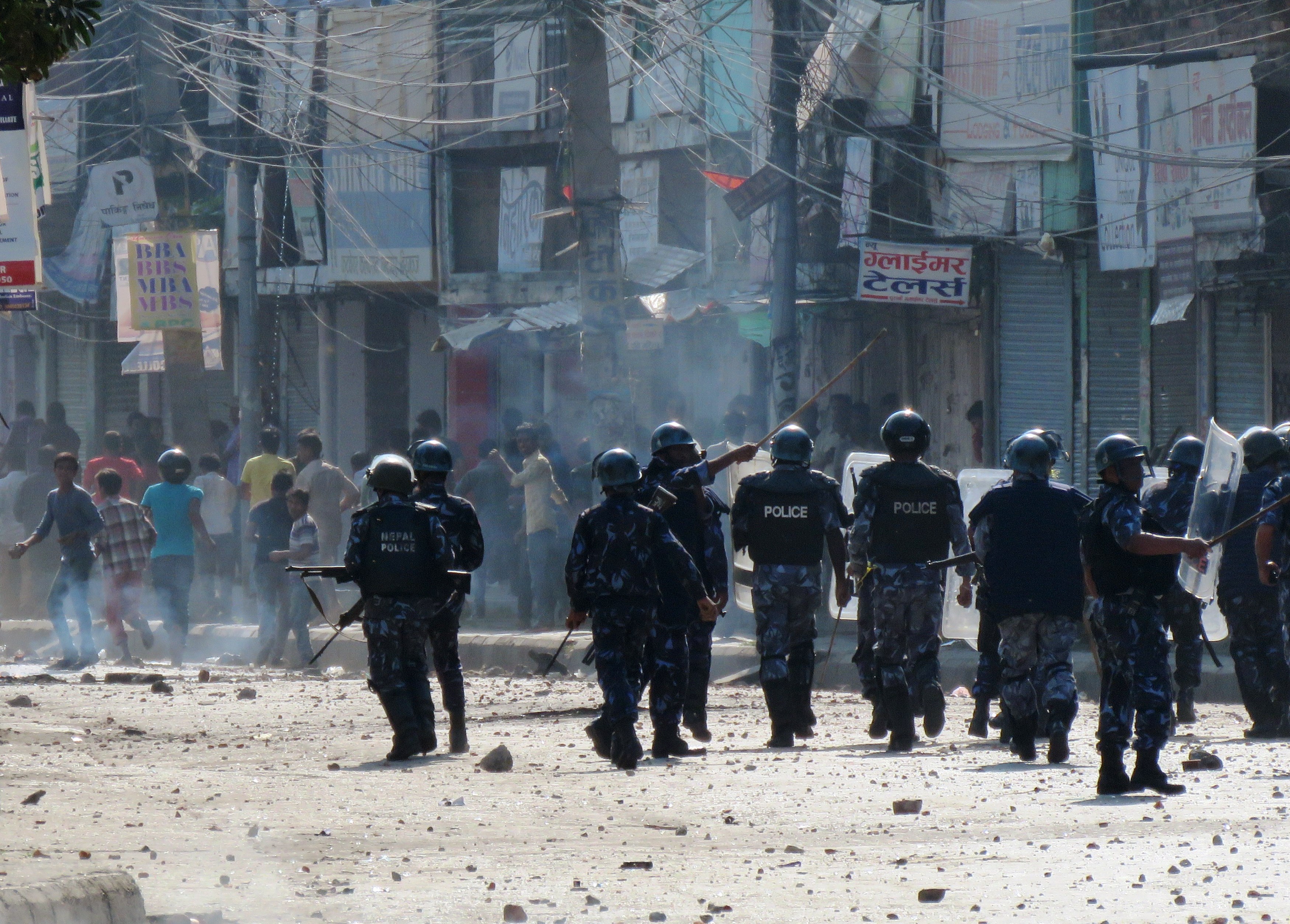 Nepalese police walk by protesters throwing rocks during clashes near the Nepal-India border at Birgunj, on Nov. 2, 2015. Police fired into a crowd of protesters trying to block a key border checkpoint and killed an Indian civilian as anger over a new constitution boiled over. (STR—AFP/Getty Images)
