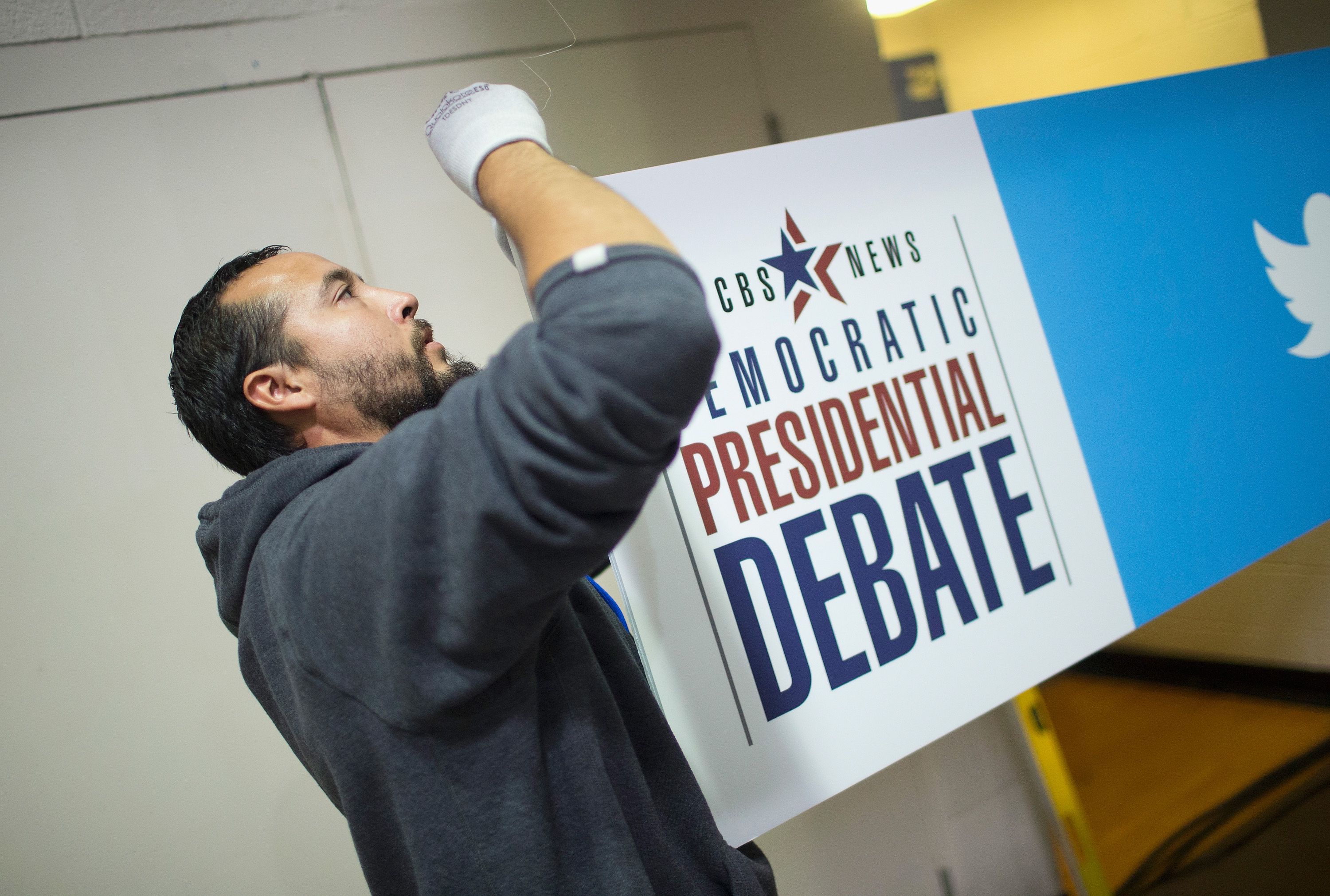 Daniel Rodriguez hangs a sign in the media file center being constructed on the campus of Drake University for tomorrows Democratic presidential debate on November 13, 2015 in Des Moines, Iowa. The debate will be the second for the democratic candidates seeking the nomination for president. (Scott Olson—Getty Images)