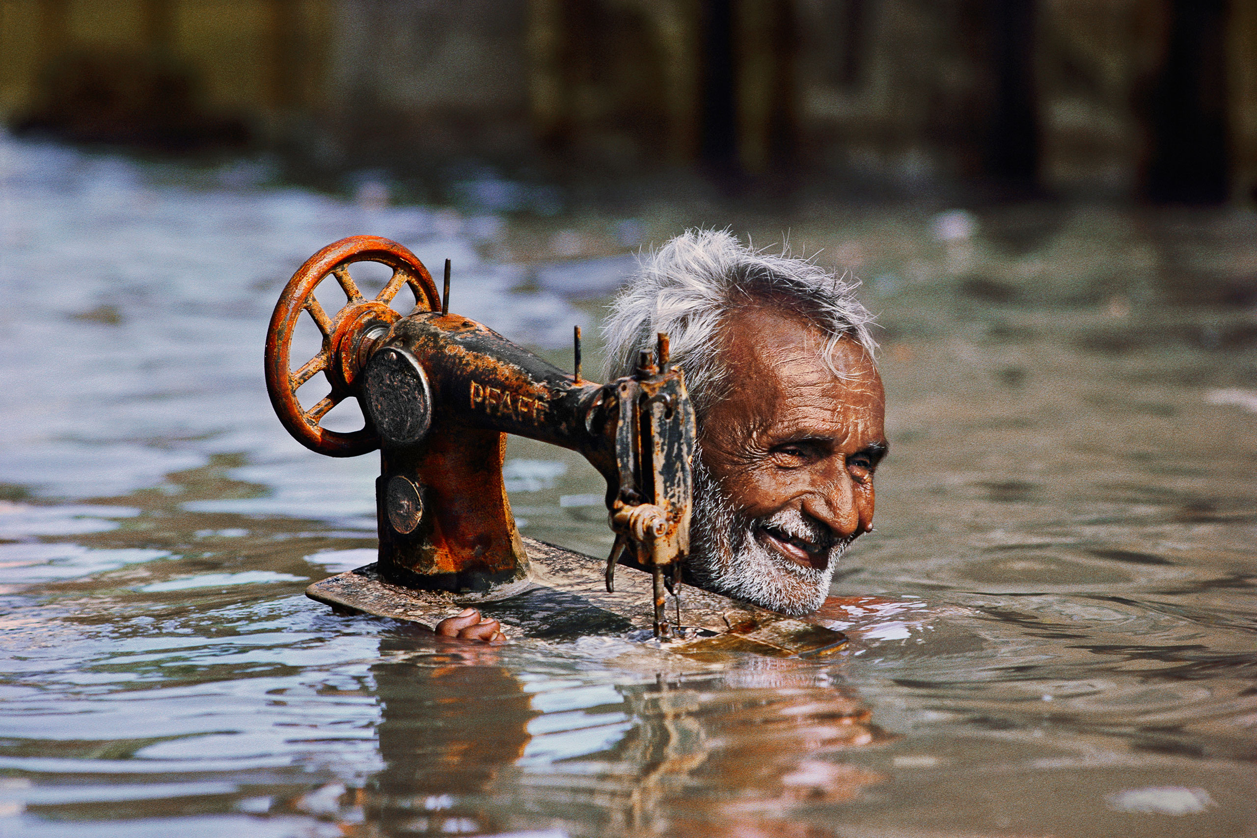 Tailor carries his sewing machine through monsoon floodwaters.
                              Porbandar, Gujarat, 1983