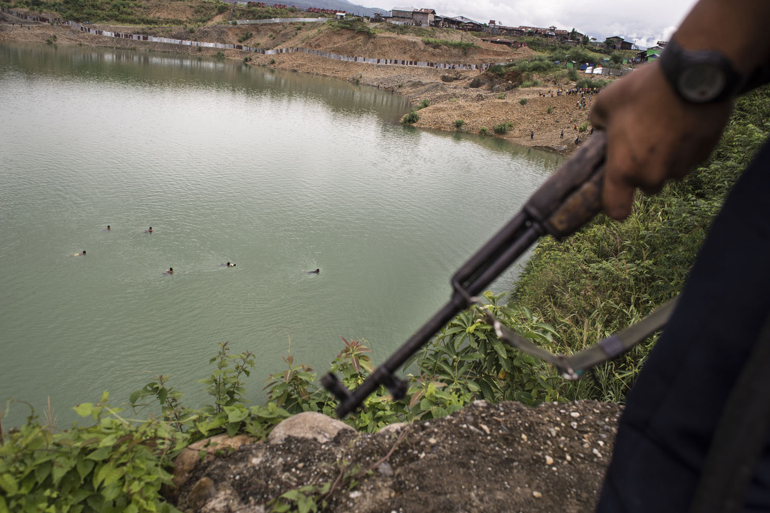 A group of illegal jade miners swim across the water as they try to escape an arrest by the police and the military forces, in a jade mining site, Hpakant, July 2014. Military officials say the miners are illegal and endangering a school located above. But the miners say they are being extorted for bribe money, which could be as much as 50,000 kyats ($40) per head