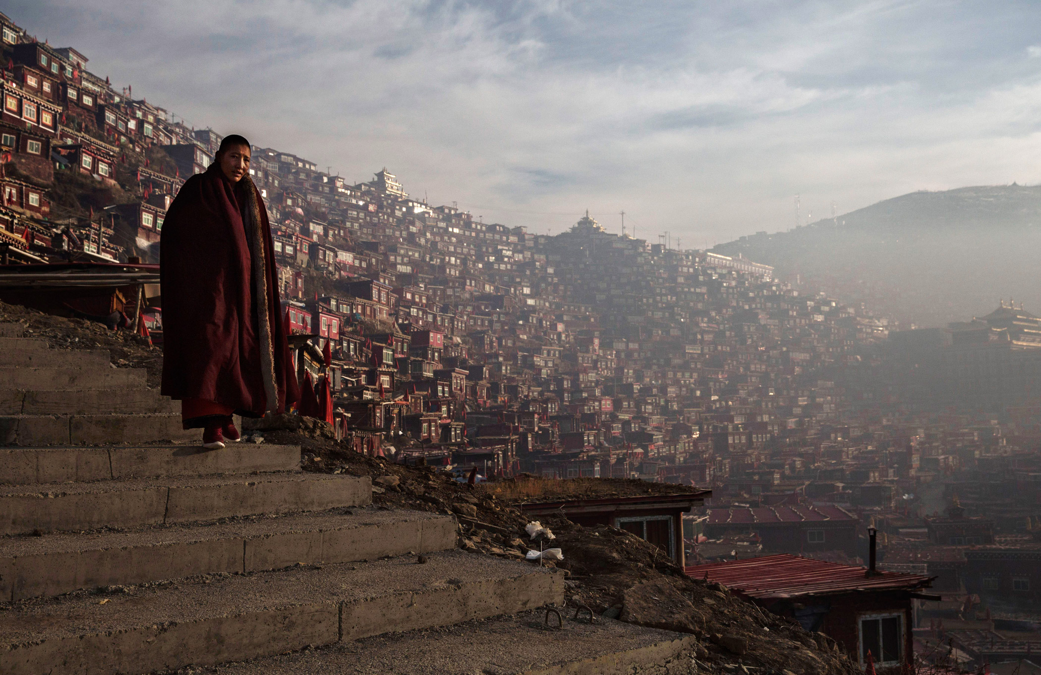 A Tibetan Buddhist nun walks passed dwellings on her way to a chanting session.