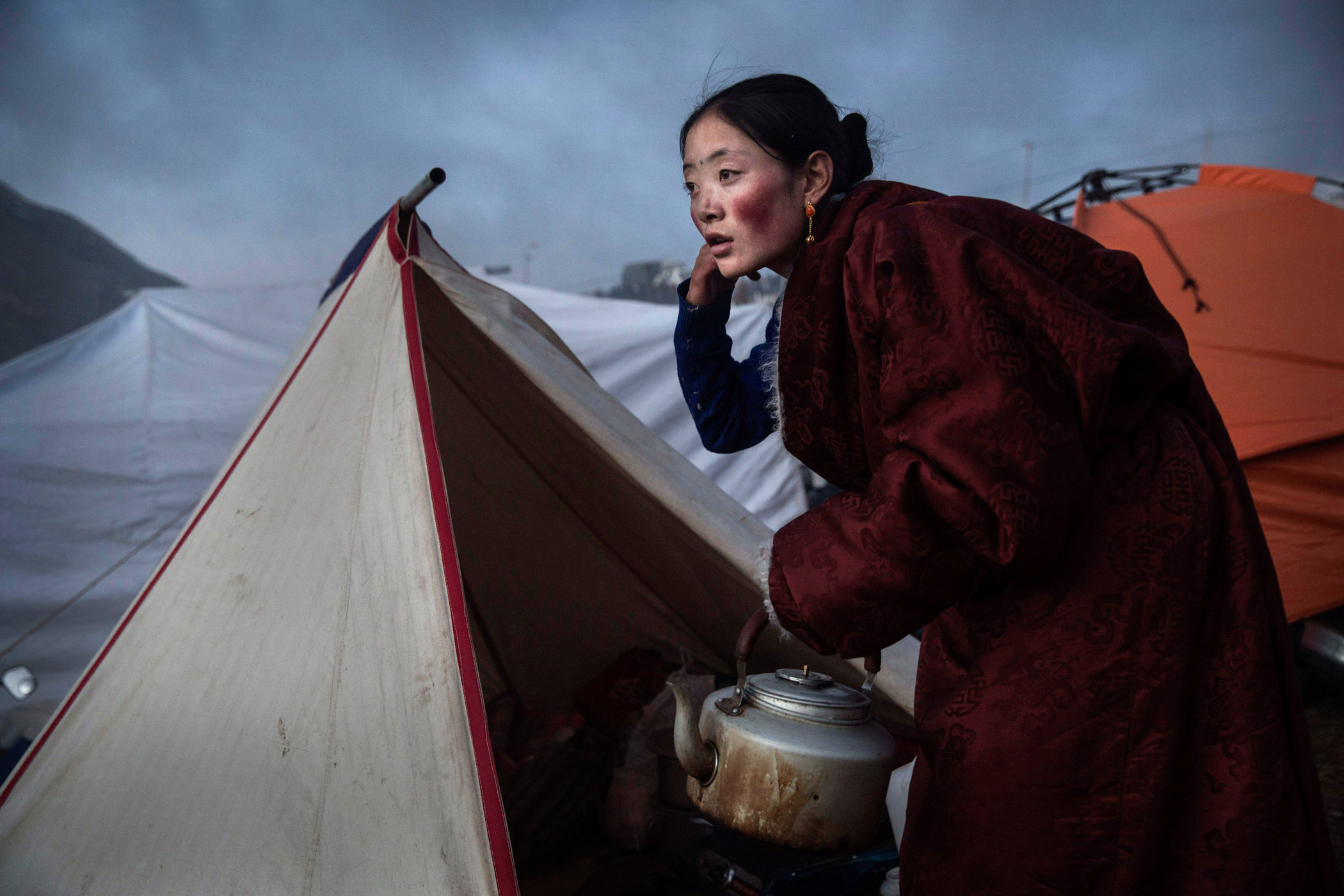 A Tibetan Buddhist nomad woman prepares tea at dusk following a chanting session.
