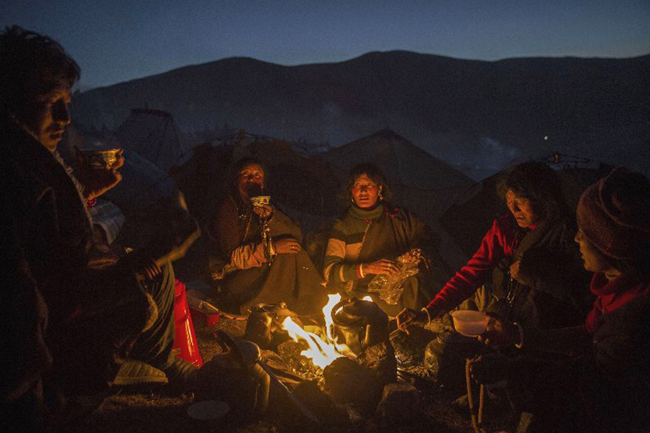 Tibetan Buddhist nomads cook on a fire at dusk during the annual Bliss Dharma Assembly.