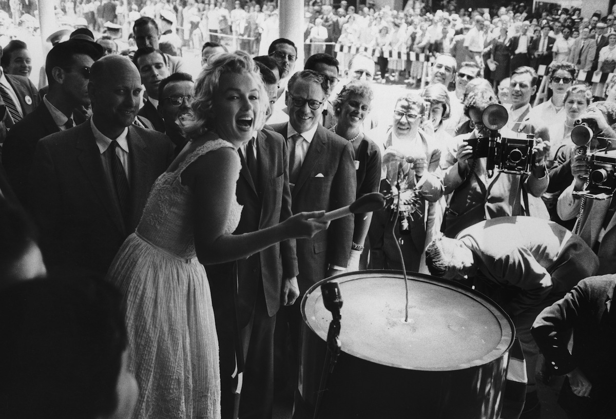 Circa 1960:  American actor Marilyn Monroe (1926 - 1962) uses an outsize match to light a large firecracker during the ribbon cutting ceremony at the Time-Life Building in New York City. (Walter Daran / Getty Images)