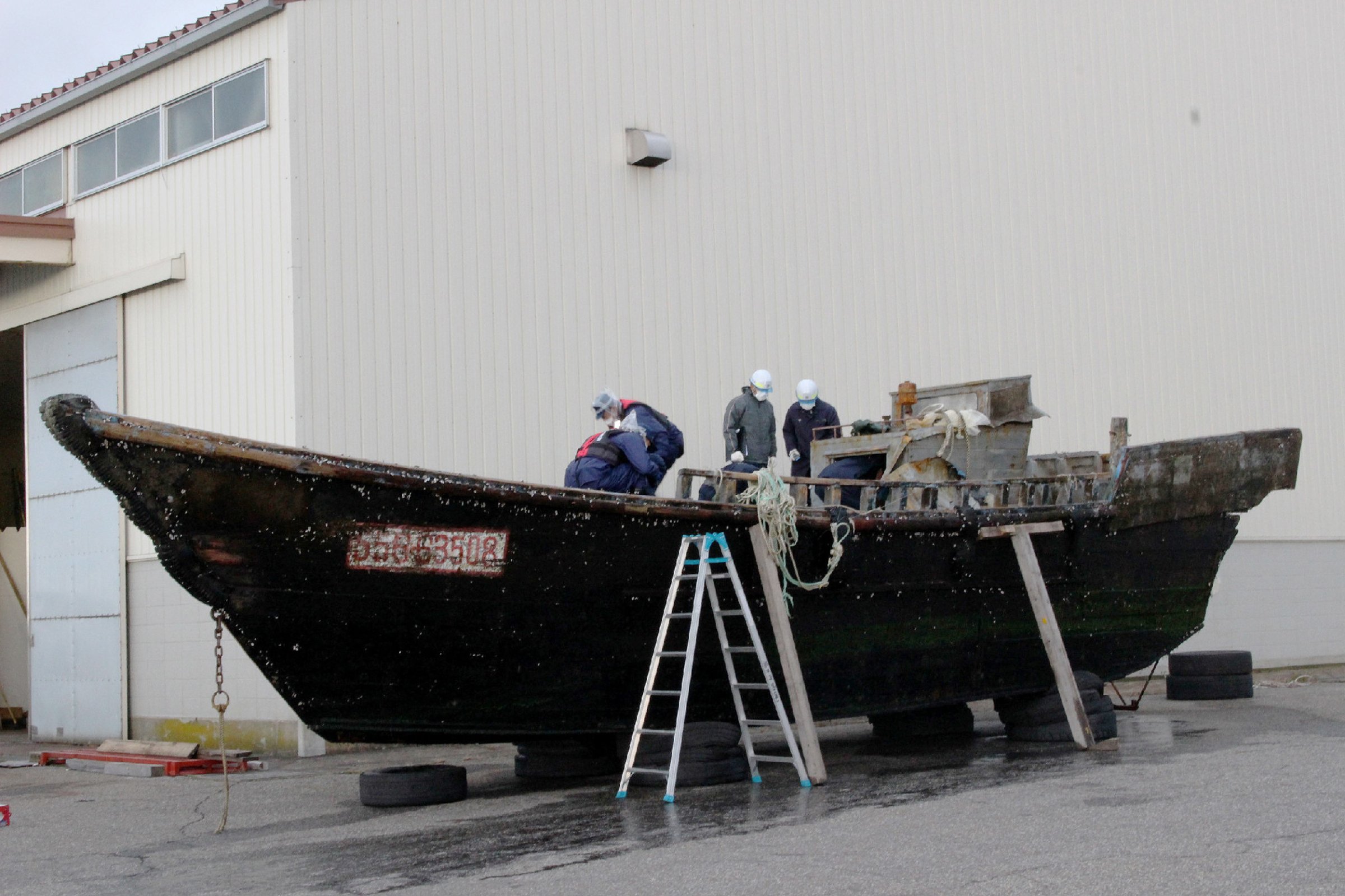This picture taken on November 24, 2015 shows coast guard officials investigating a wooden boat at the Fukui port in Sakai city in Fukui prefecture, western Japan after the ship was found drifting off the coast of Fukui.