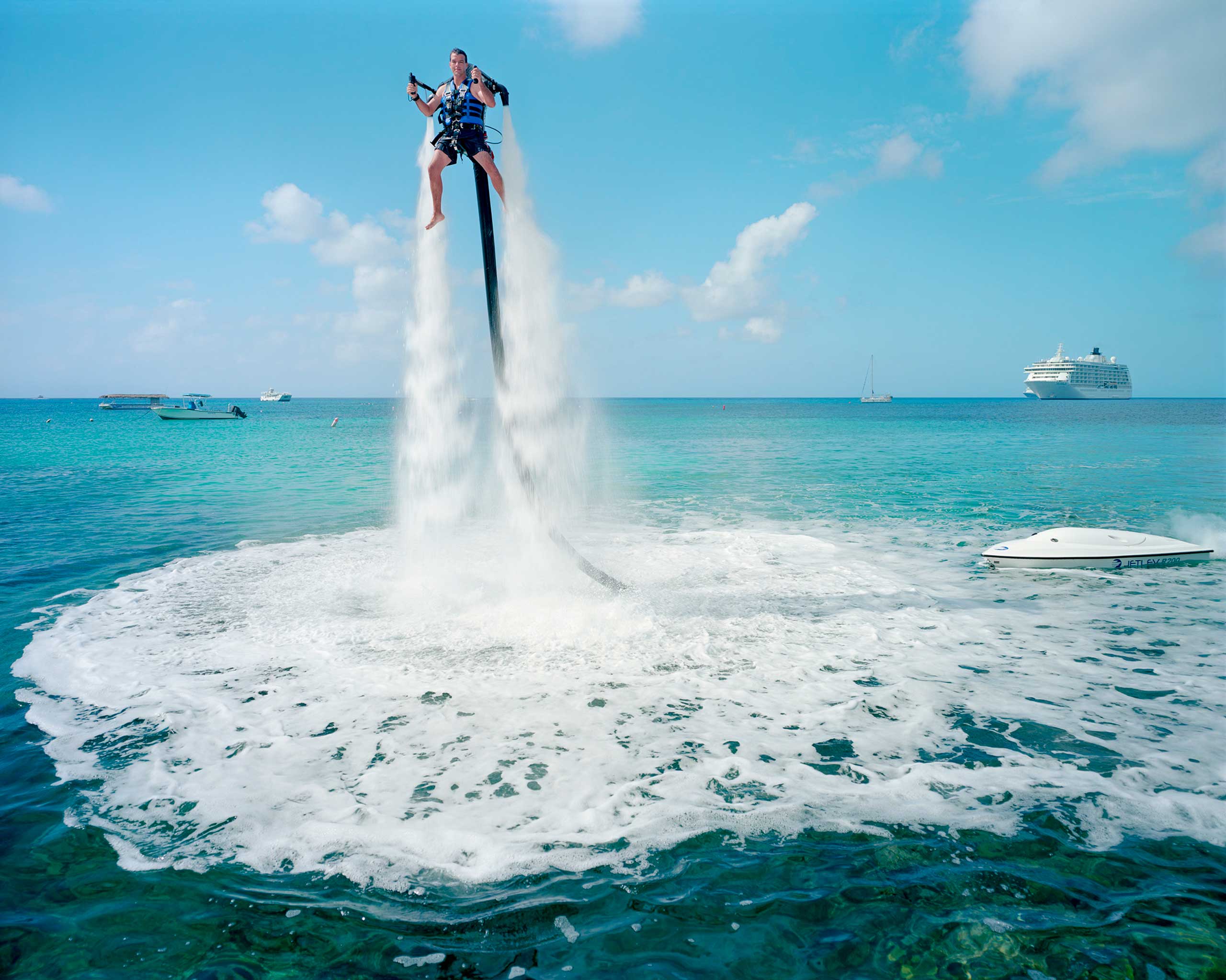 An employee of “Jetpack Cayman” demonstrates this new watersport, now available on the island. A 2000cc motor pumps water up through the Jetpack, propelling the client out of the sea ($359 for a 30-minute session). Mike Thalasinos, the owner of the company, remarks, “The Jetpack is zero gravity, the Cayman are zero taxes, we are in the right place!” Grand Cayman. (Gabriele Galimberti and Paolo Woods—Institute)