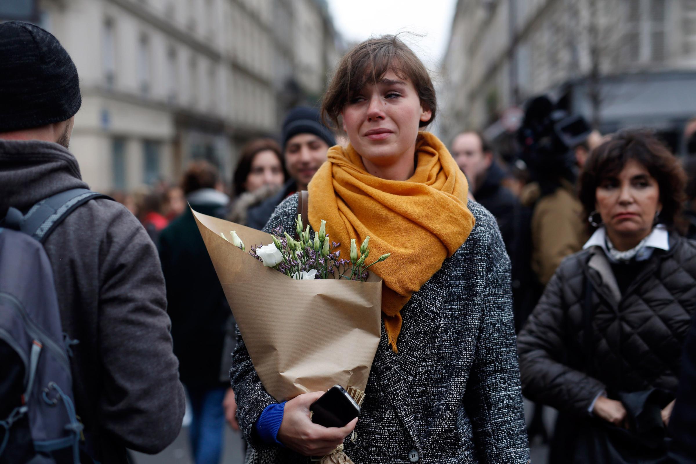 A woman carrying flowers cries in front of the Carillon cafe and the Petit Cambodge restaurant in Paris on Nov. 14, 2015.