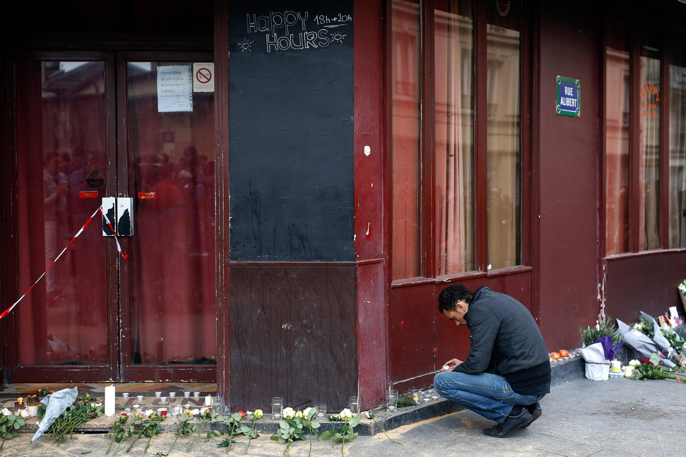 A man places a candle in front of the Carillon cafe in Paris on Nov. 14, 2015.