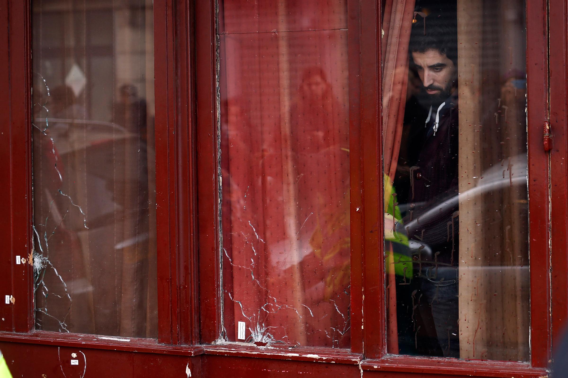 A man looks out the bullet ridden windows of the Carillon cafe in Paris on Nov. 14, 2015.