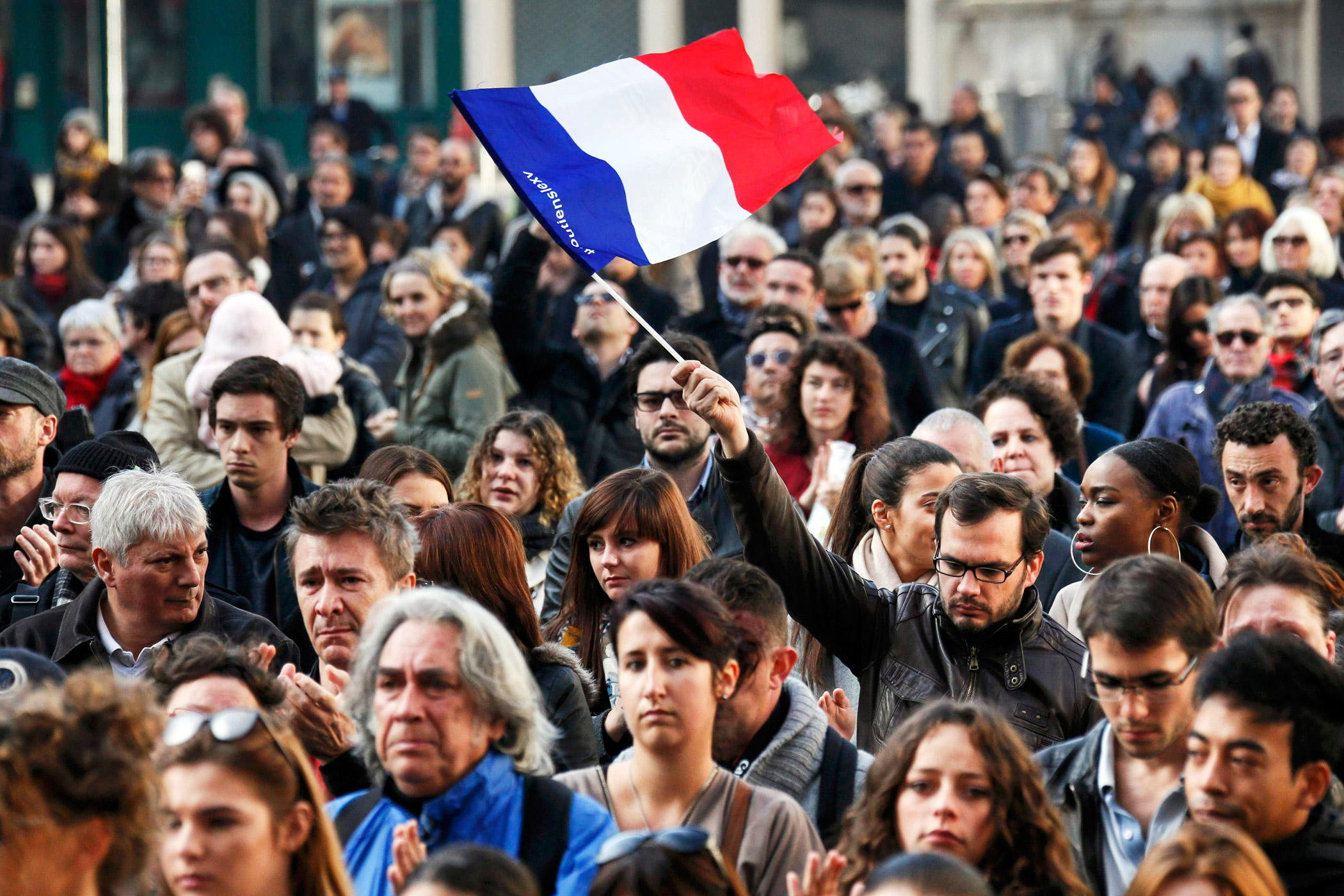 A man waves a French flag during a minute of silence in Lyon, France.