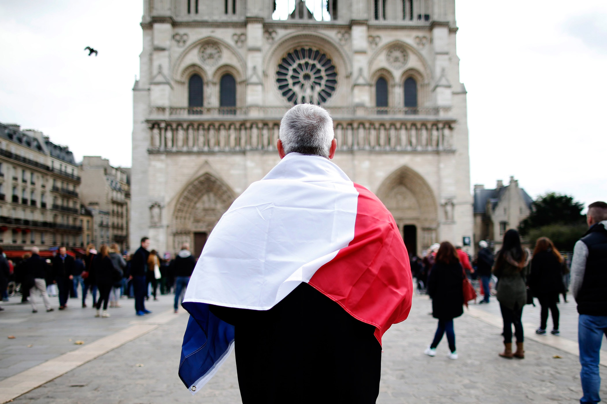 A man observes a minute of silence in front of the Notre Dame Cathedral in Paris.