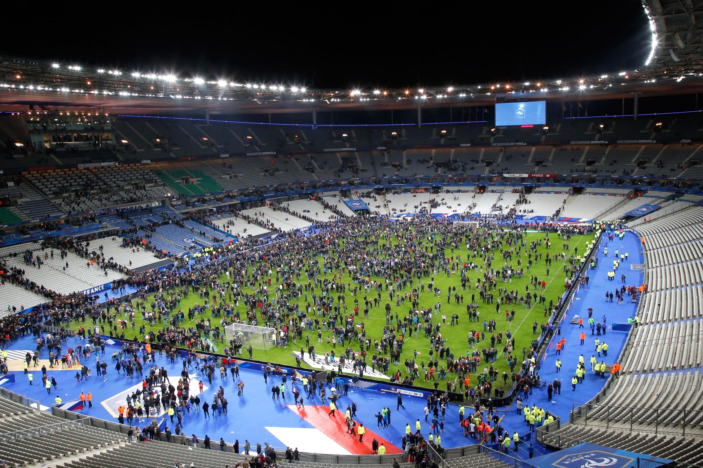 Spectators invade the pitch of the Stade de France stadium after the international friendly soccer France against Germany, Friday, Nov. 13, 2015 in Saint Denis, outside Paris. At least 35 people were killed in shootings and explosions around Paris, many of them in a popular theater where patrons were taken hostage, police and medical officials said Friday. Two explosions were heard outside the Stade de France stadium. (AP Photo/Michel Euler)