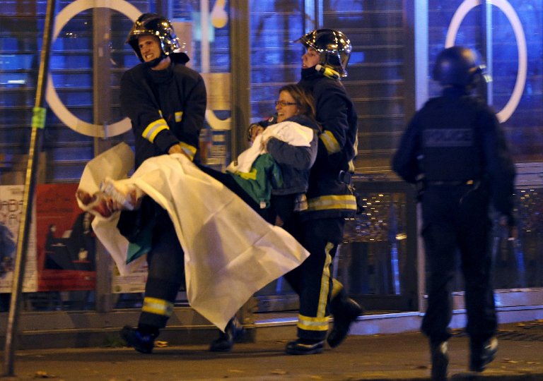 French fire brigade members carry an injured individual near the concert hall following fatal shootings in Paris, on Nov. 13, 2015.