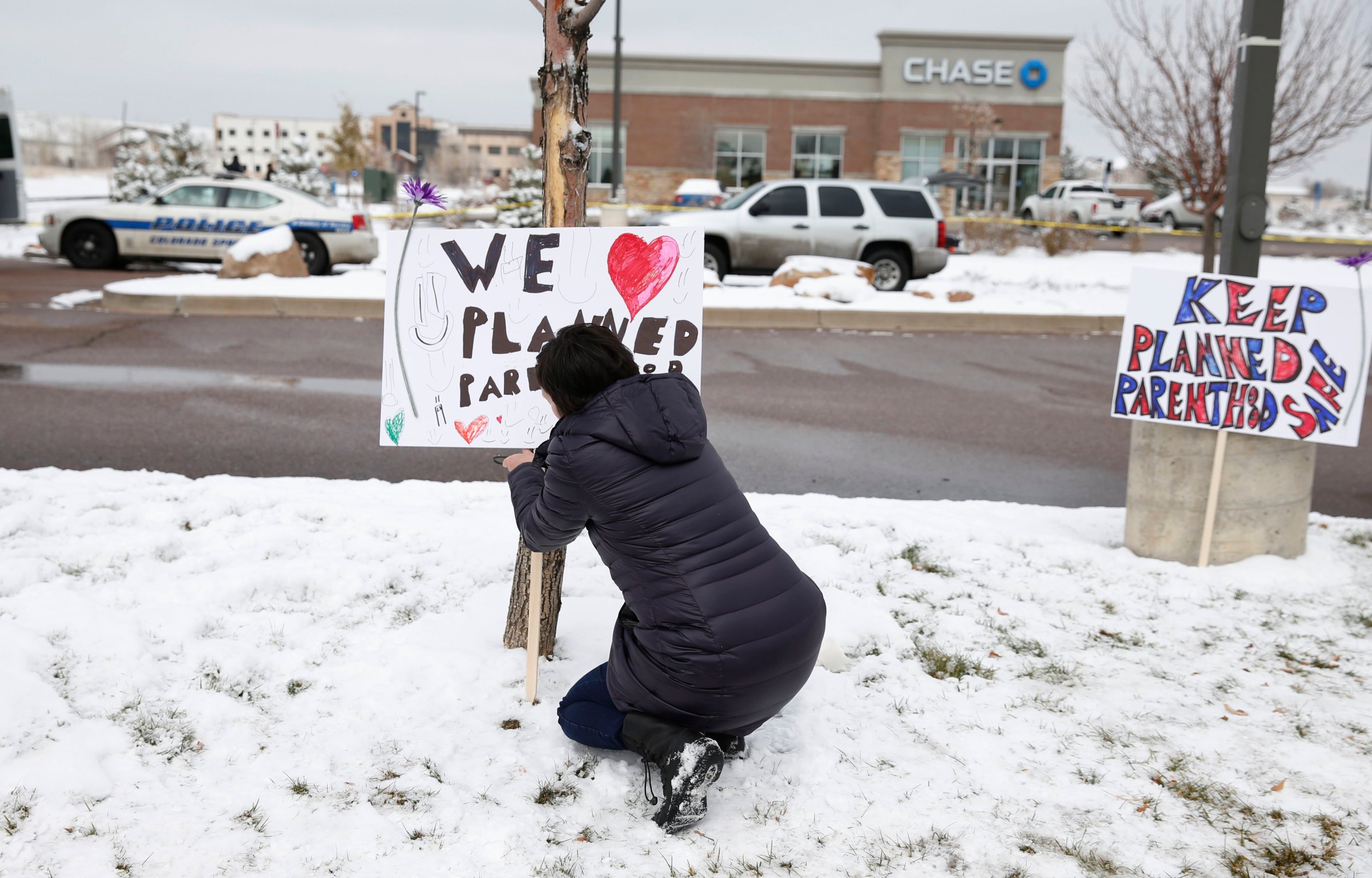 Bethany Winder, a nurse who lives in Colorado Springs, Colo., plants a sign in support of Planned Parenthood just south of its clinic as police investigators gather evidence near the scene of Friday's shooting at the clinic on Nov. 29, 2015.