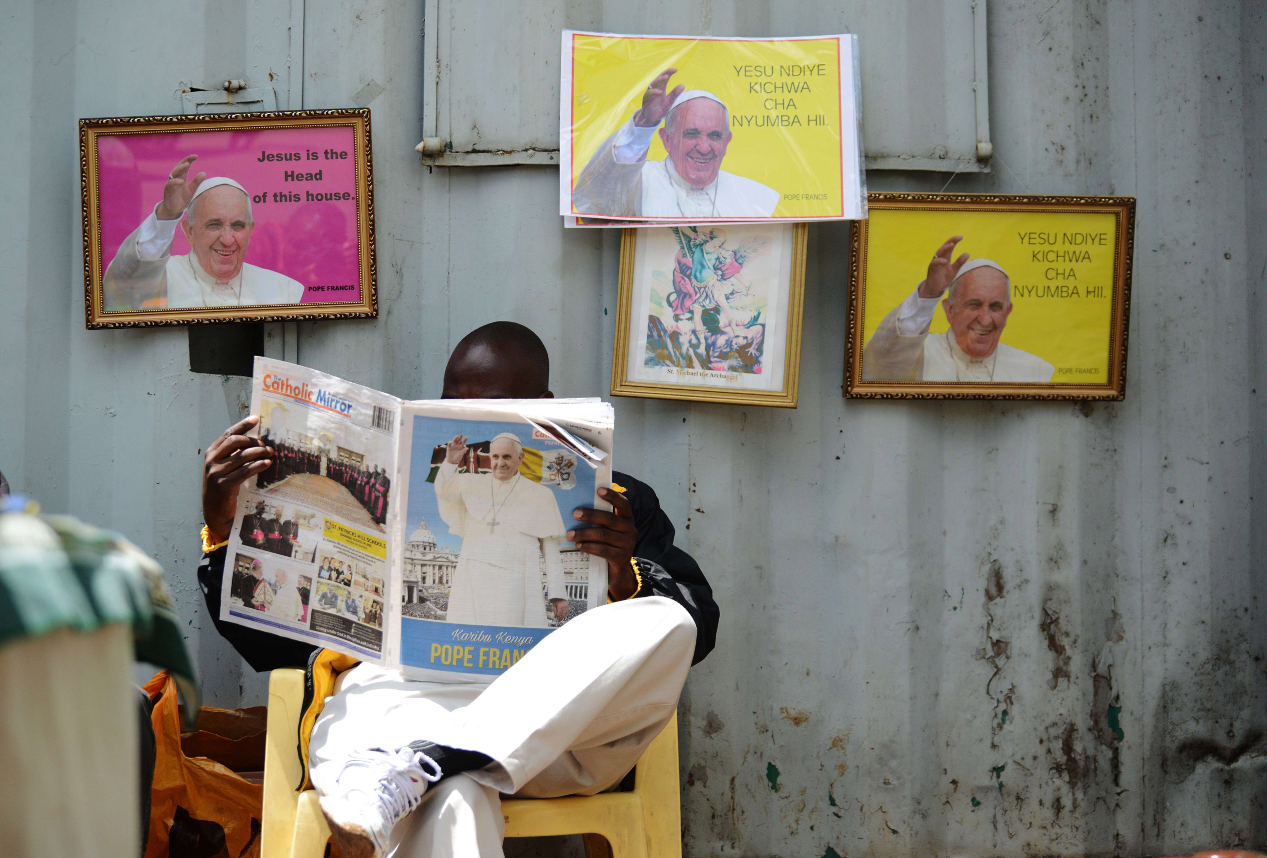 A man reads a copy of the  Catholic Mirror  newspaper next to pictures of Pope Francis at the Holy Family Basilica in Nairobi on Nov. 22, 2015.