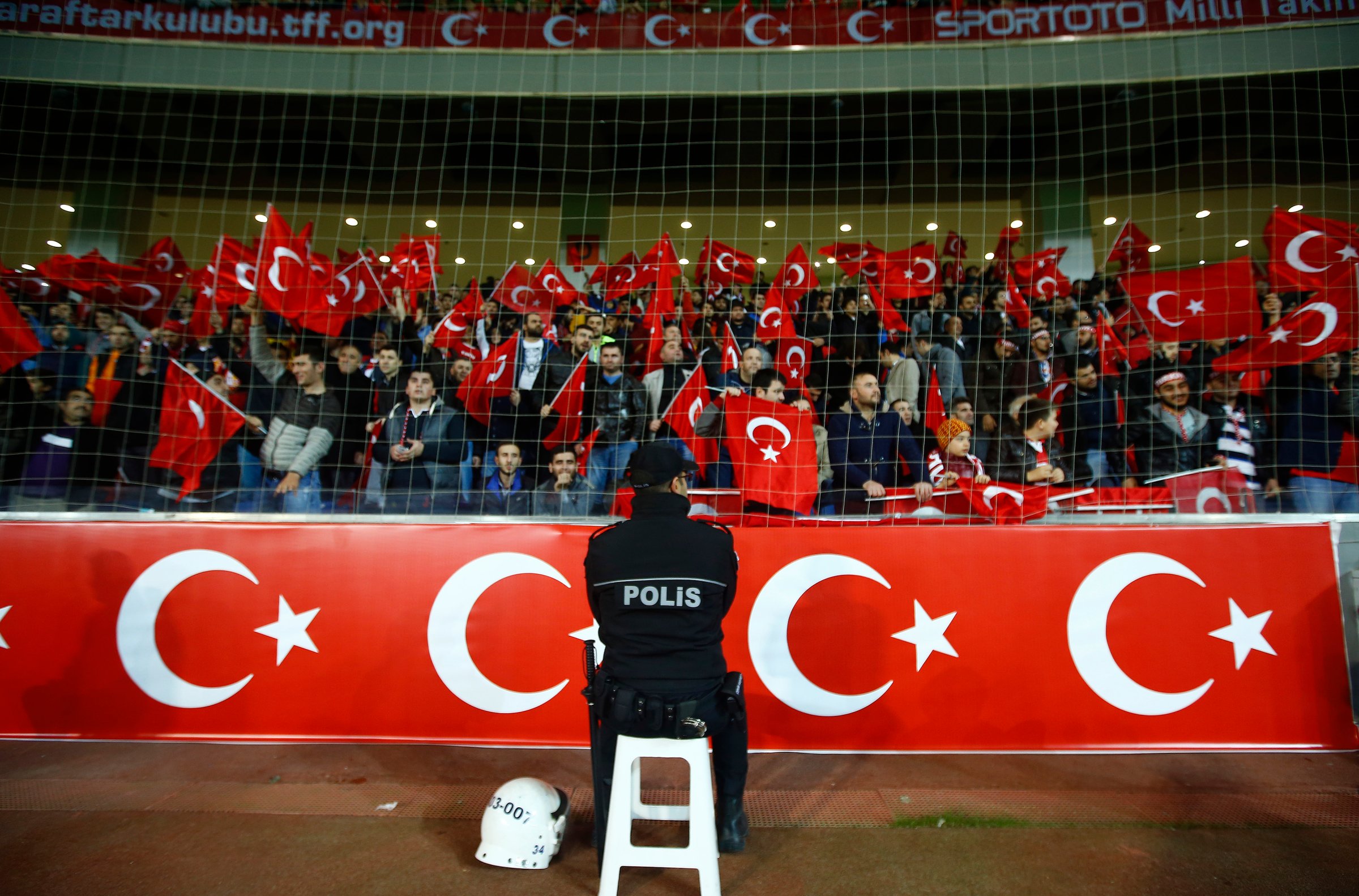 Policeman stands guard in front of supporters of Turkey during their international friendly soccer match against Greece at Basaksehir Fatih Terim stadium in Istanbul