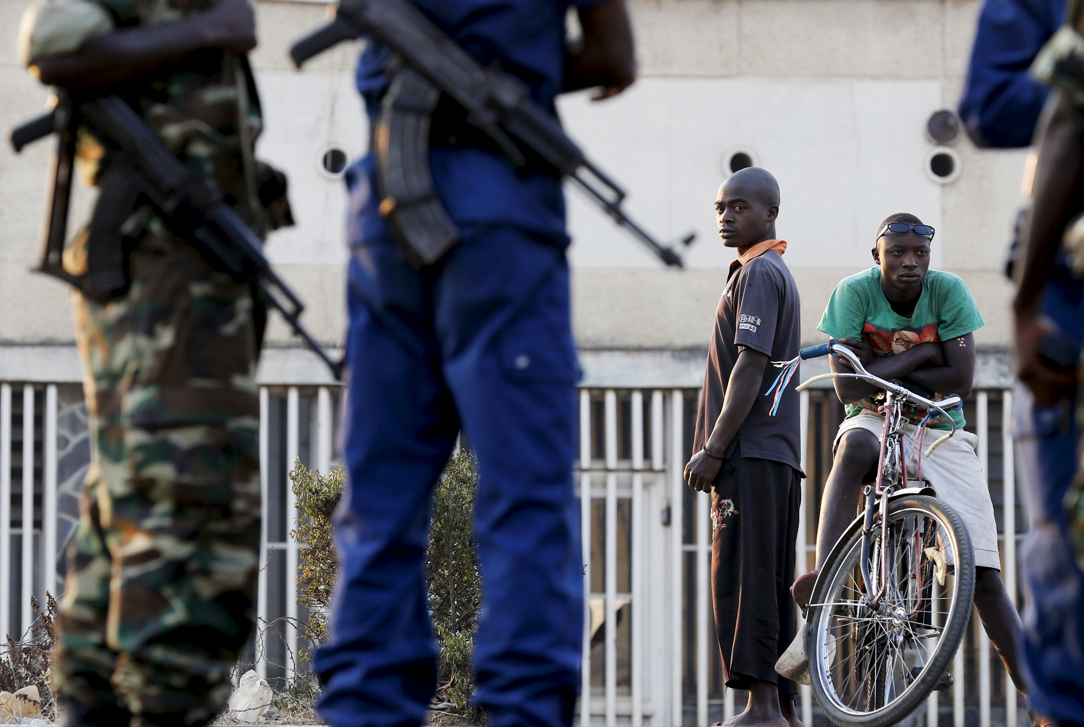 Residents look on as police and soldiers guard a voting station in Burundi's capital Bujumbura during the country's presidential election