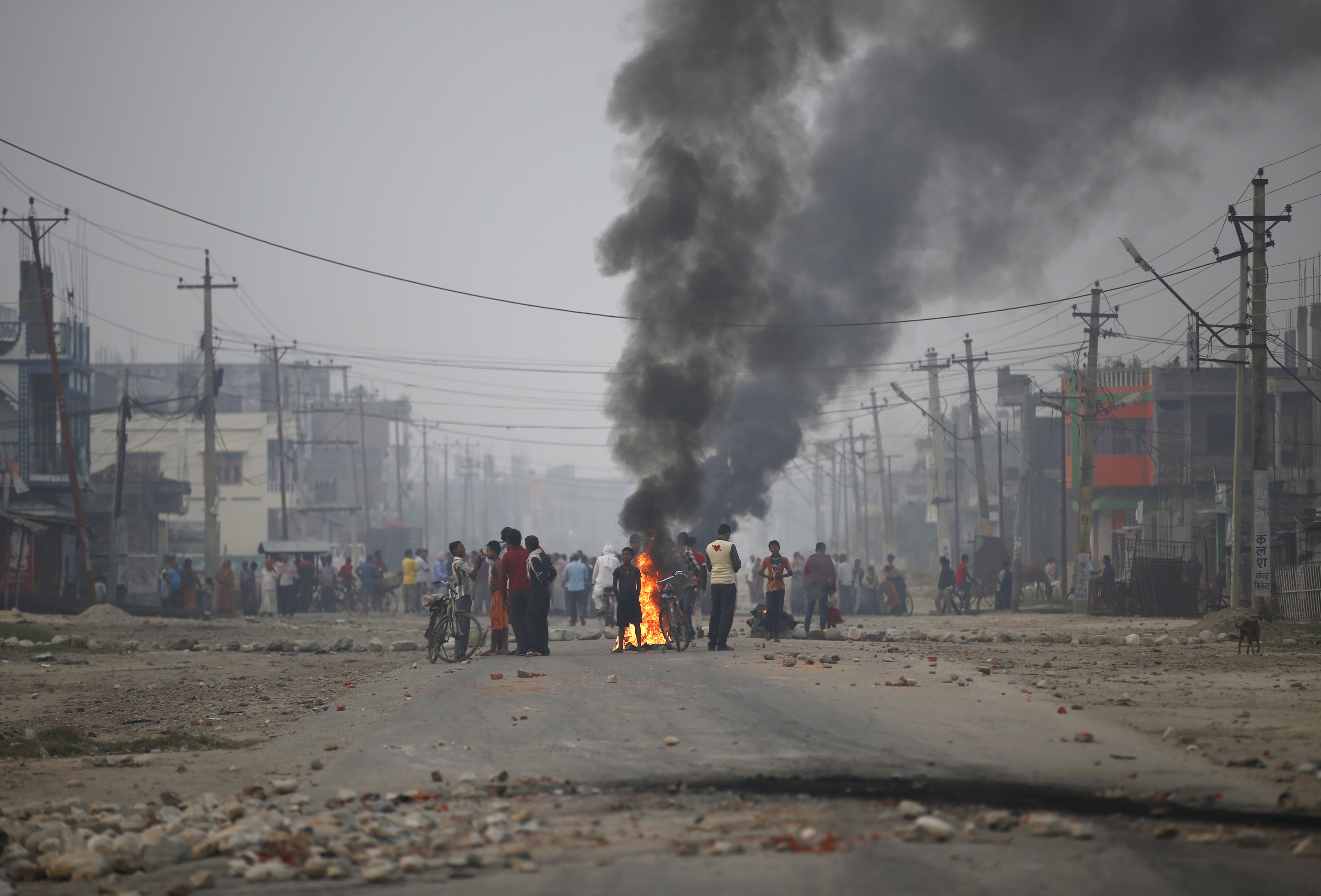 Protesters stand near burning tyres as they gather to block highway connecting Nepal and India, during general strike called by Madhesi protesters demonstrating against new constitution in Birgunj