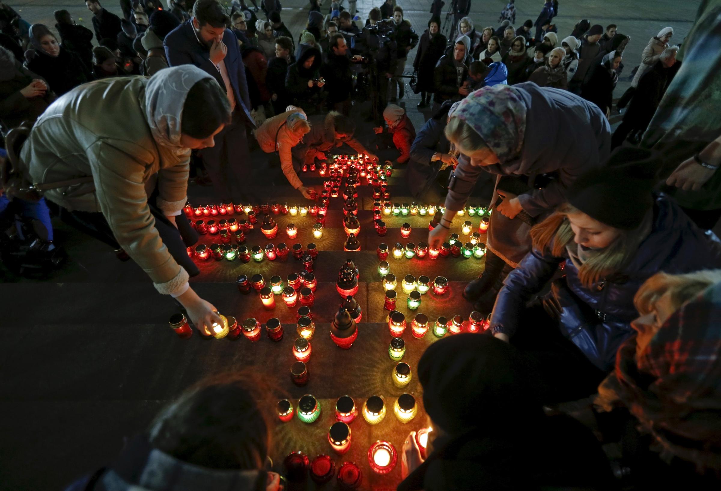 People arrange candles to make a cross to commemorate 224 victims of a Russian airliner which crashed in Egypt, on the stairs of the Christ the Saviour Cathedral in Moscow, Russia, November 1, 2015. An Airbus A321, operated by Russian airline Kogalymavia under the brand name Metrojet, carrying 224 passengers crashed into a mountainous area of Egypt's Sinai peninsula on Saturday shortly after losing radar contact near cruising altitude, killing all aboard. Russian President Vladimir Putin declared a day of national mourning for Sunday. REUTERS/Maxim Shemetov - RTX1U9UO
