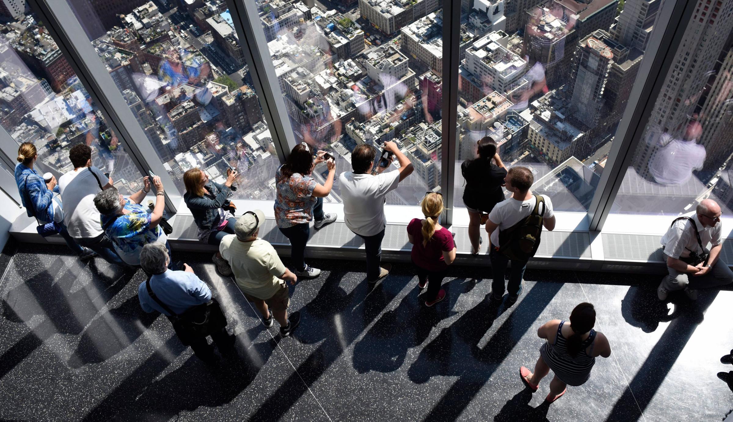 Visitors look out over city streets from the One World Observatory at One World Trade Center, in New York. May 29, 2015.