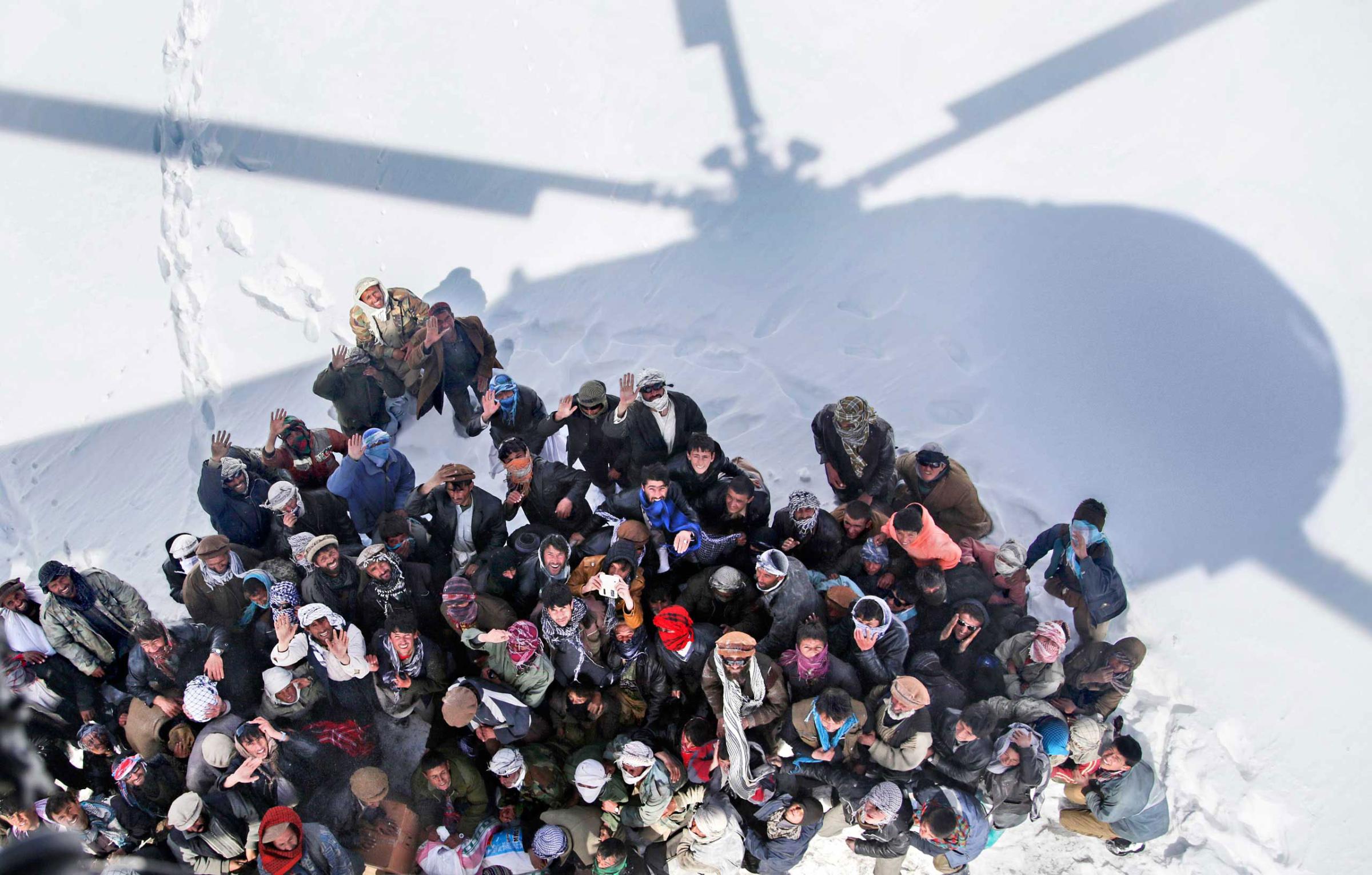 Survivors of an avalanche wait to receive relief goods distributed by an Army helicopter in the Paryan district of Panjshir province, Afghanistan. Feb. 28, 2015.