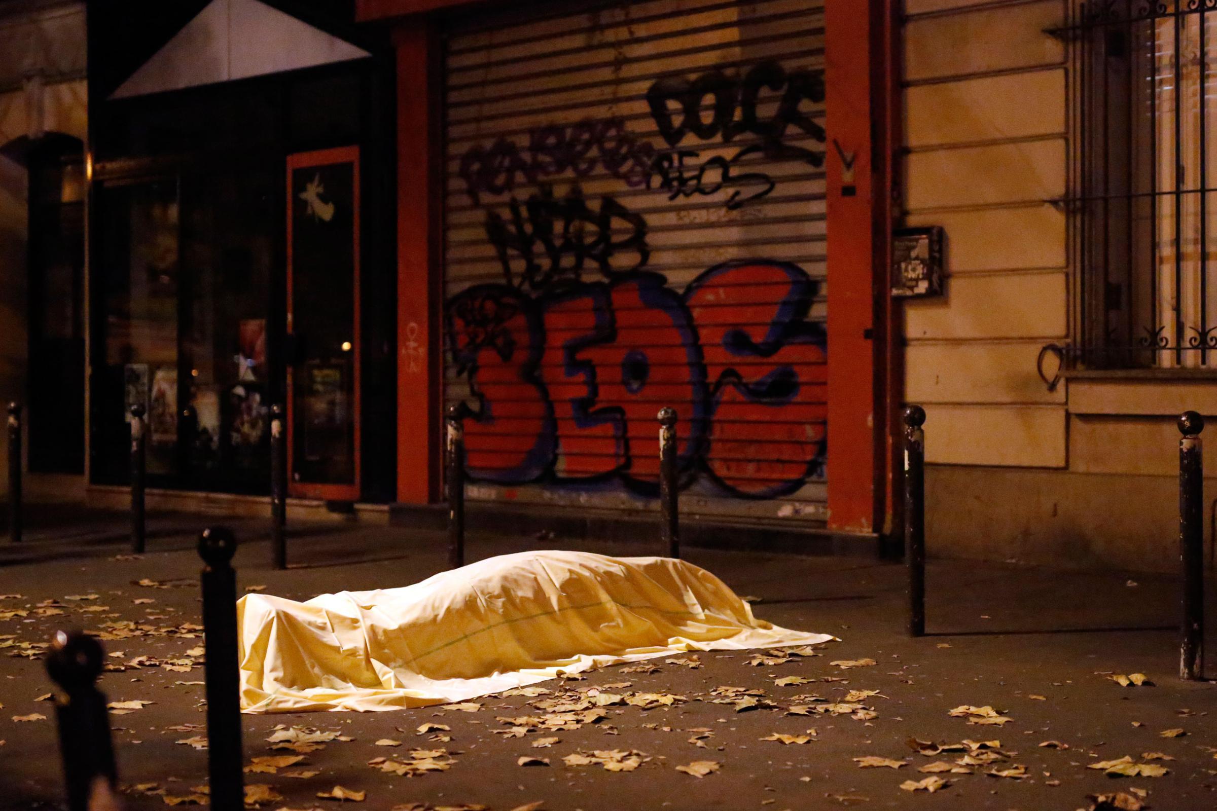 A victim under a blanket lays dead outside the Bataclan theater in Paris, France. Nov. 13, 2015. At least 129 people were killed in a series of shooting and explosions. French President Francois Hollande declared a state of emergency and announced that he was closing the country's borders.