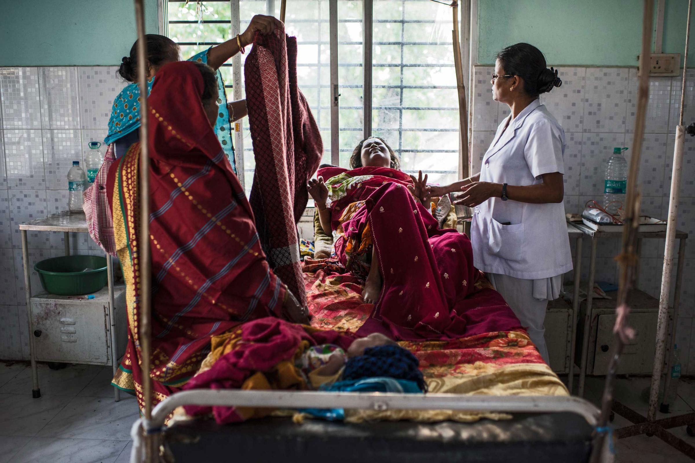 Nazreen Khatoon winces in pain as she lies gravely ill, suffering from severe postpartum anemia at the Tezpur Civil Hospital in Tezpur, Assam, India.