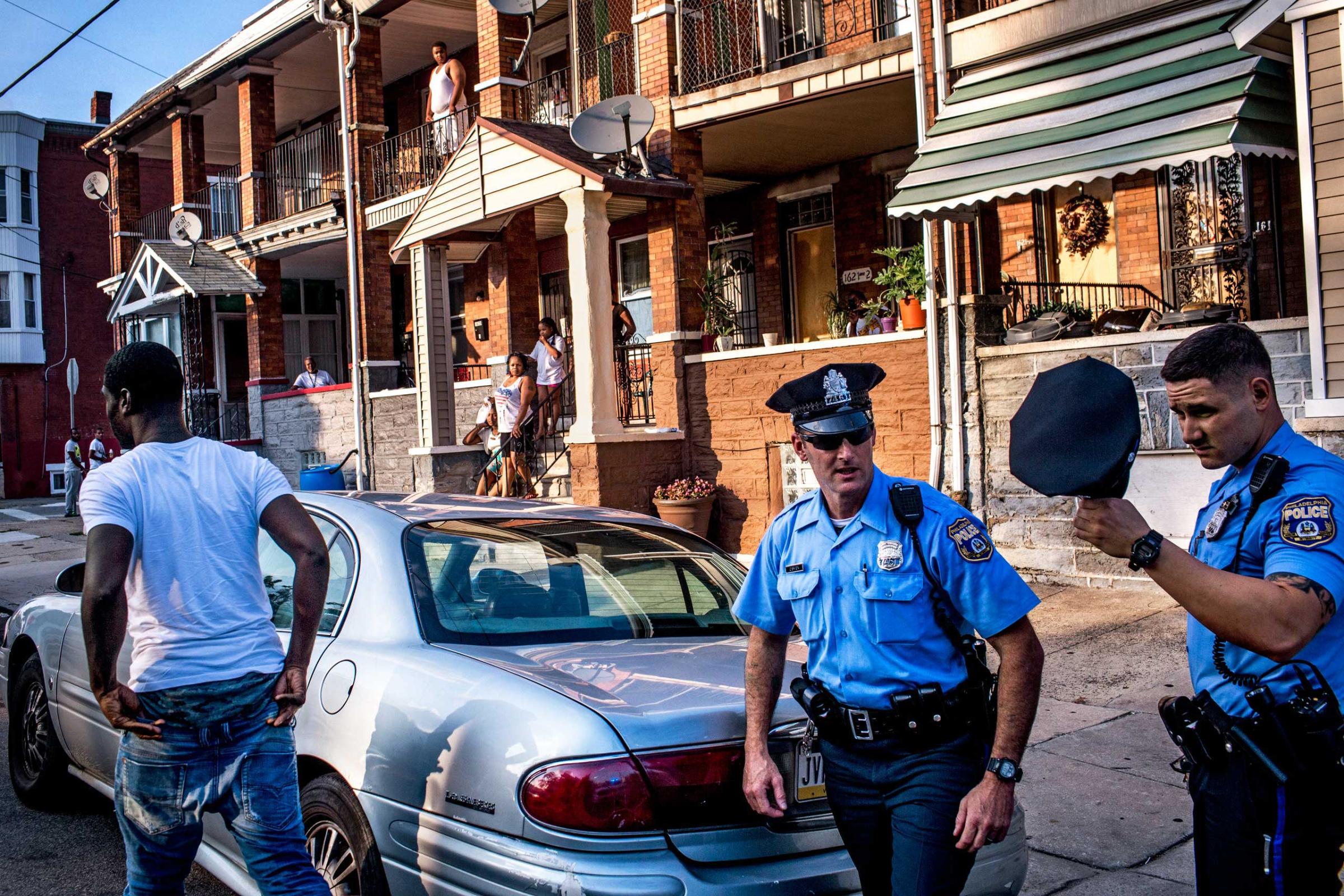 Officers Paul Watson, right, and his partner Officer Richard O'Brien make a traffic stop in Philadelphia, PA., as neighbors look on. After the police searched his car, the man was released. July 29, 2015.
