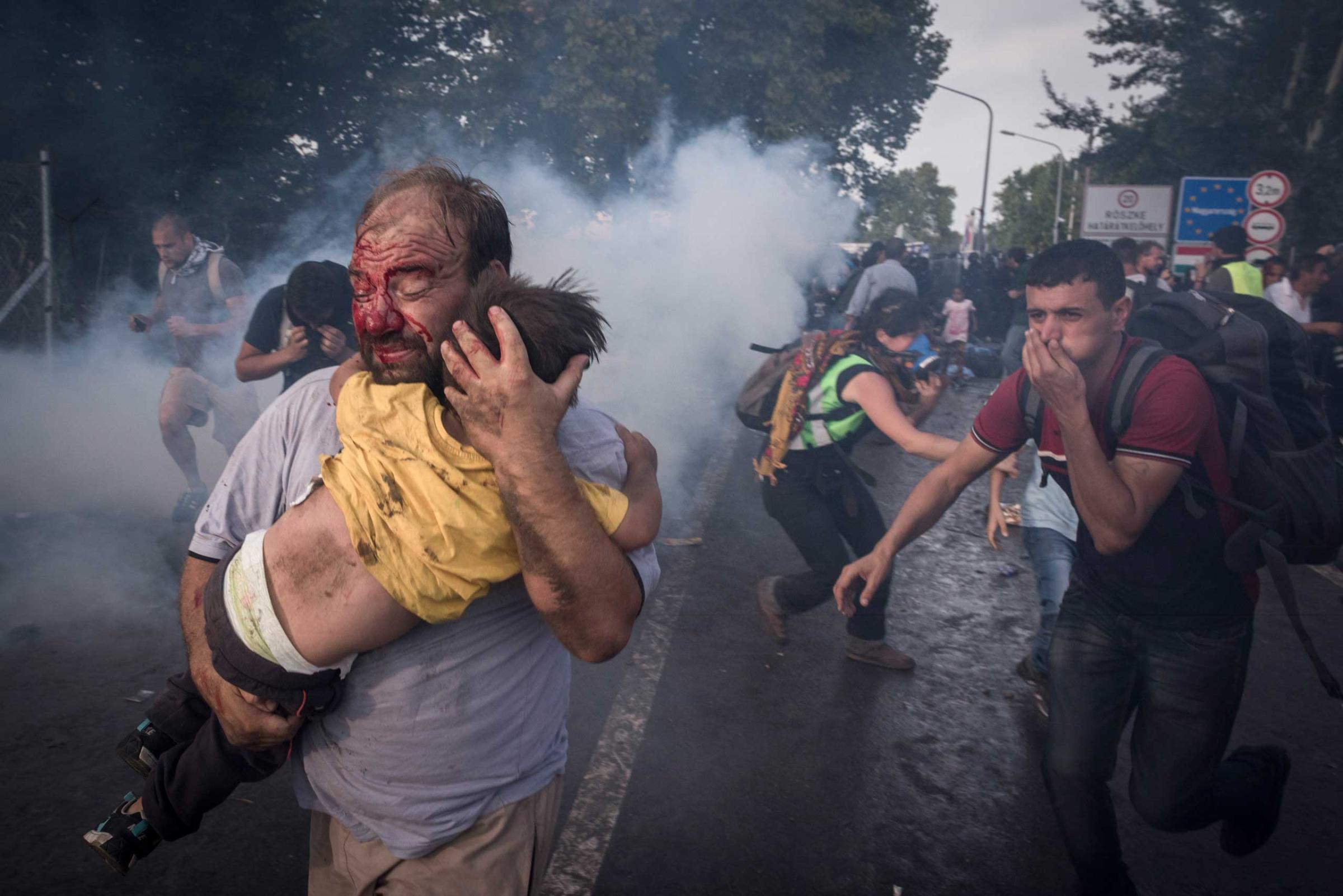 A migrant holds his child during a clash with Hungarian riot police at the Horgos border crossing in Serbia. Hungary's decision to seal its border rippled across Europe and other migrants scrambled to find alternative routes, in an effort, in most cases, to reach Germany. Sept. 16, 2015