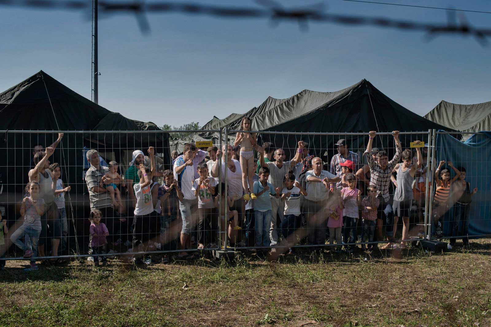 A group of migrants wait at a makeshift detention camp for Hungarian authorities in Roszke, Hungary, to register their arrival in the European Union. Aug. 29, 2015